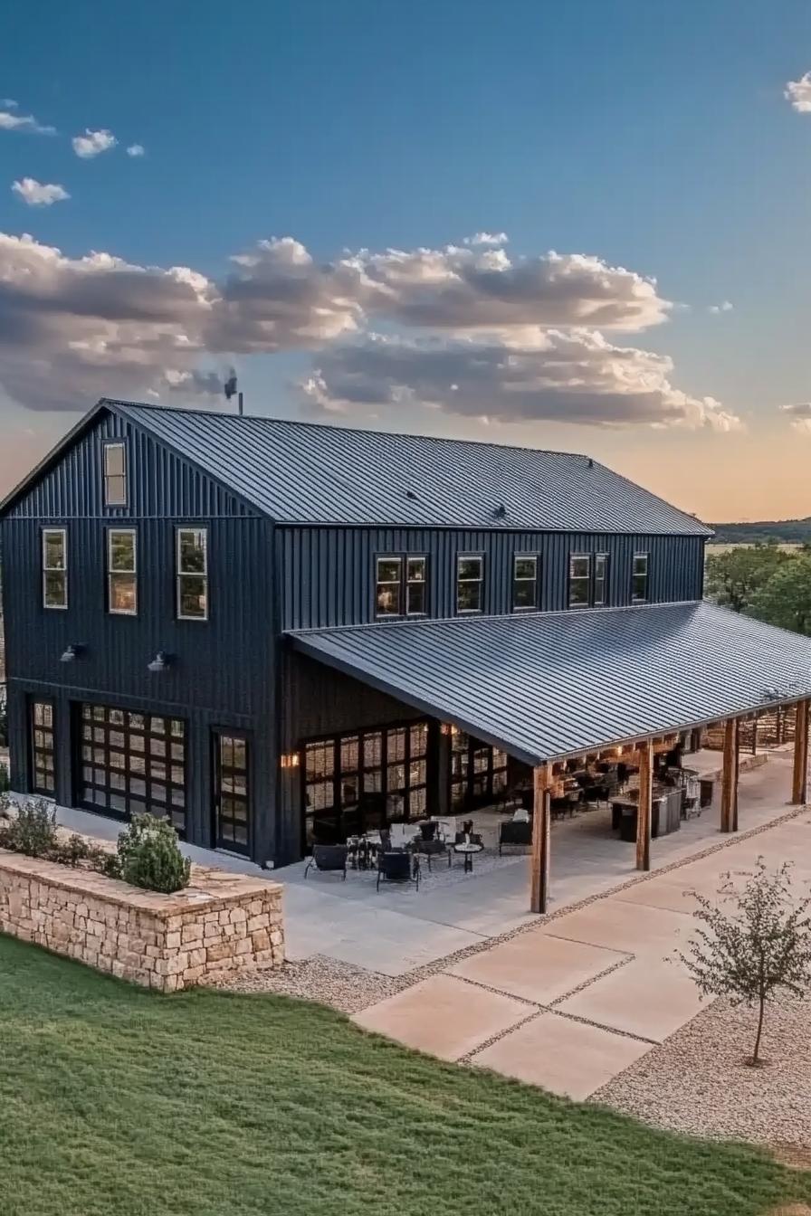 high angle view of a large black shouse barndominium with large side porch large patio and yard stone patio fence large garage doors