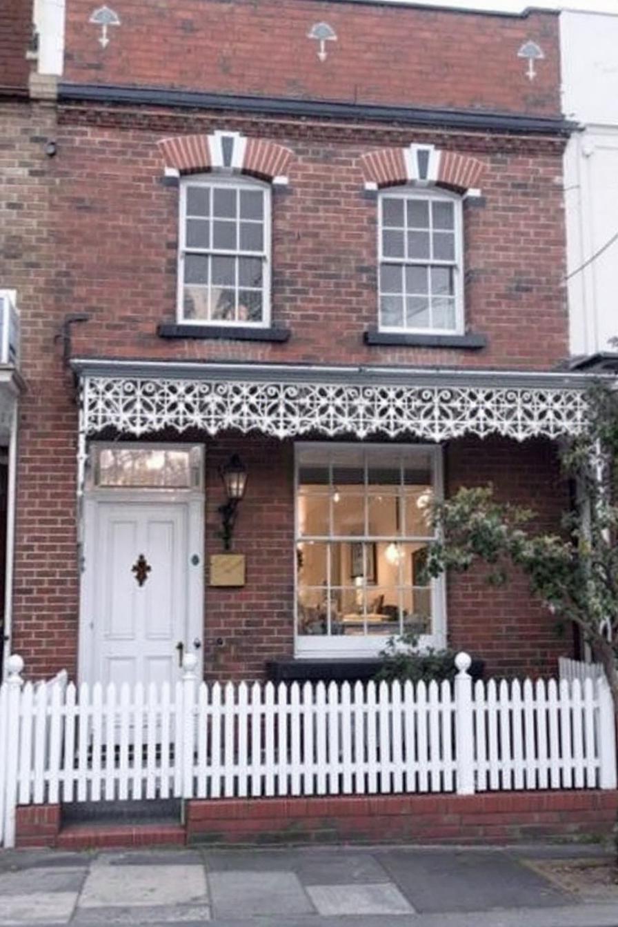 Victorian-style house with ornate ironwork and picket fence