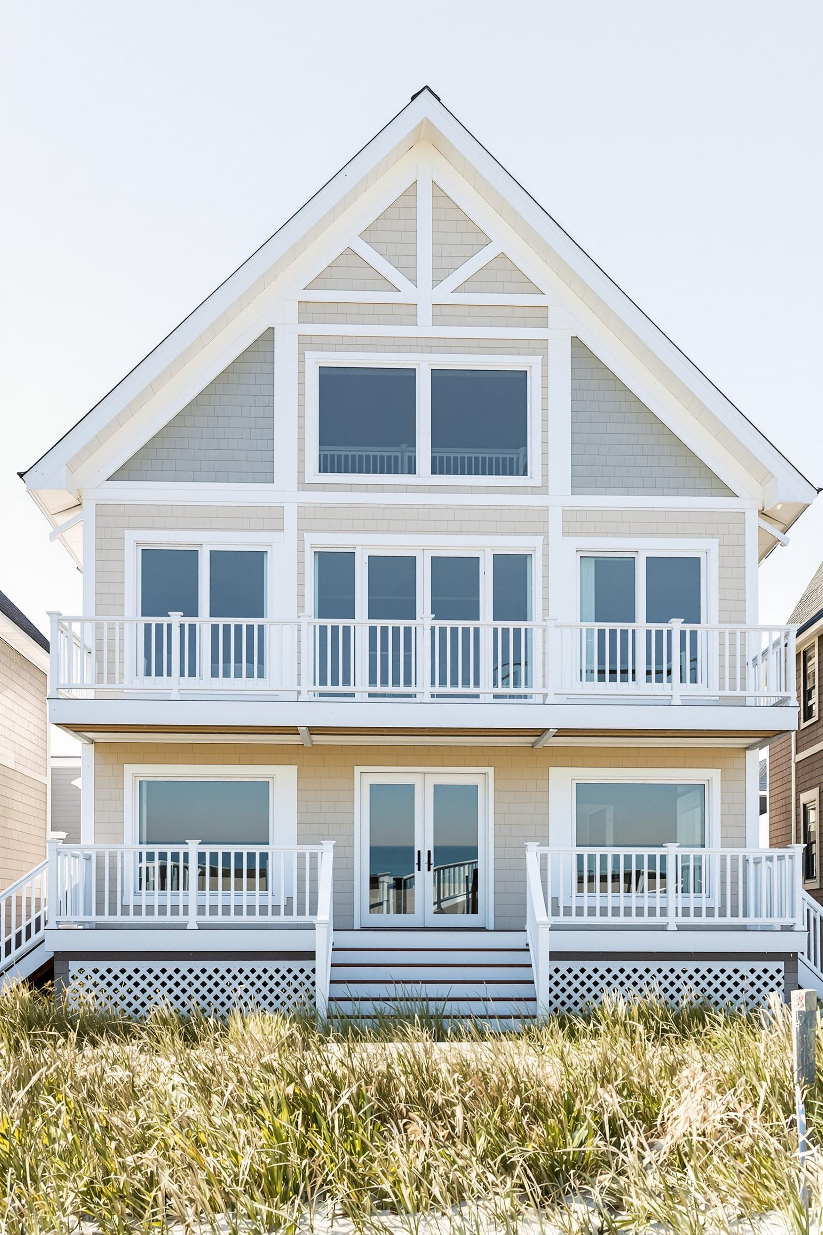 Modern beach house with balconies, large windows, and light-colored siding