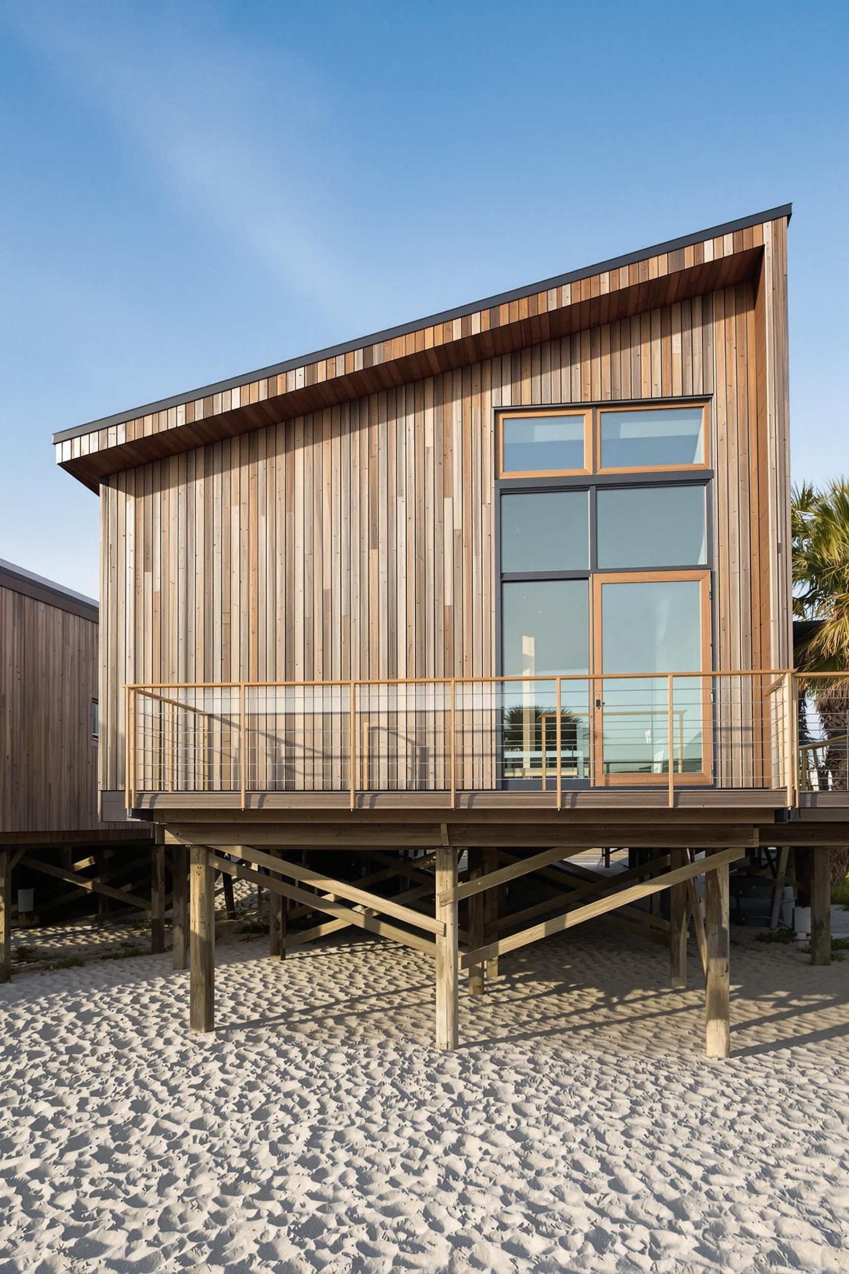 Wooden beach house on stilts with a slanted roof