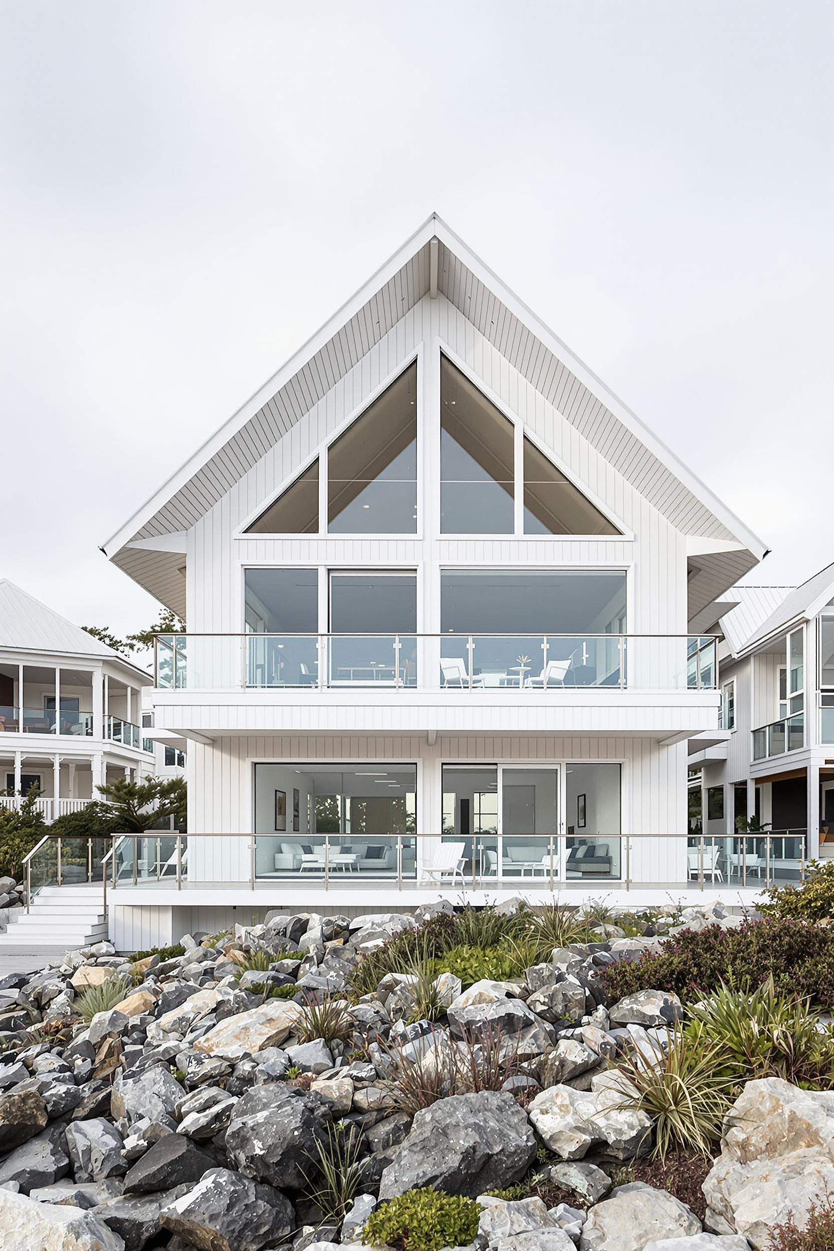 A modern beach house with a steeply pitched roof and large windows