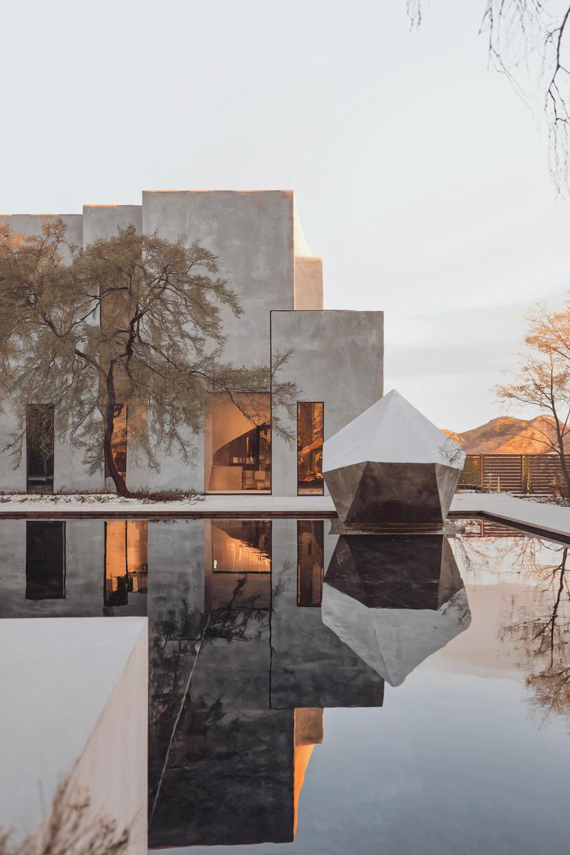 Modern house with a reflective pool and geometric sculpture