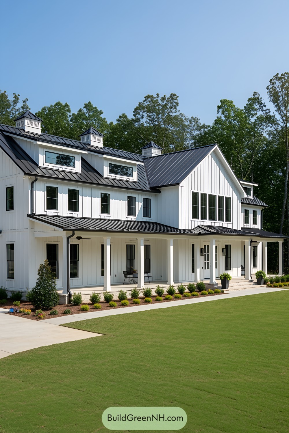 White barndominium with black metal roof in green landscape