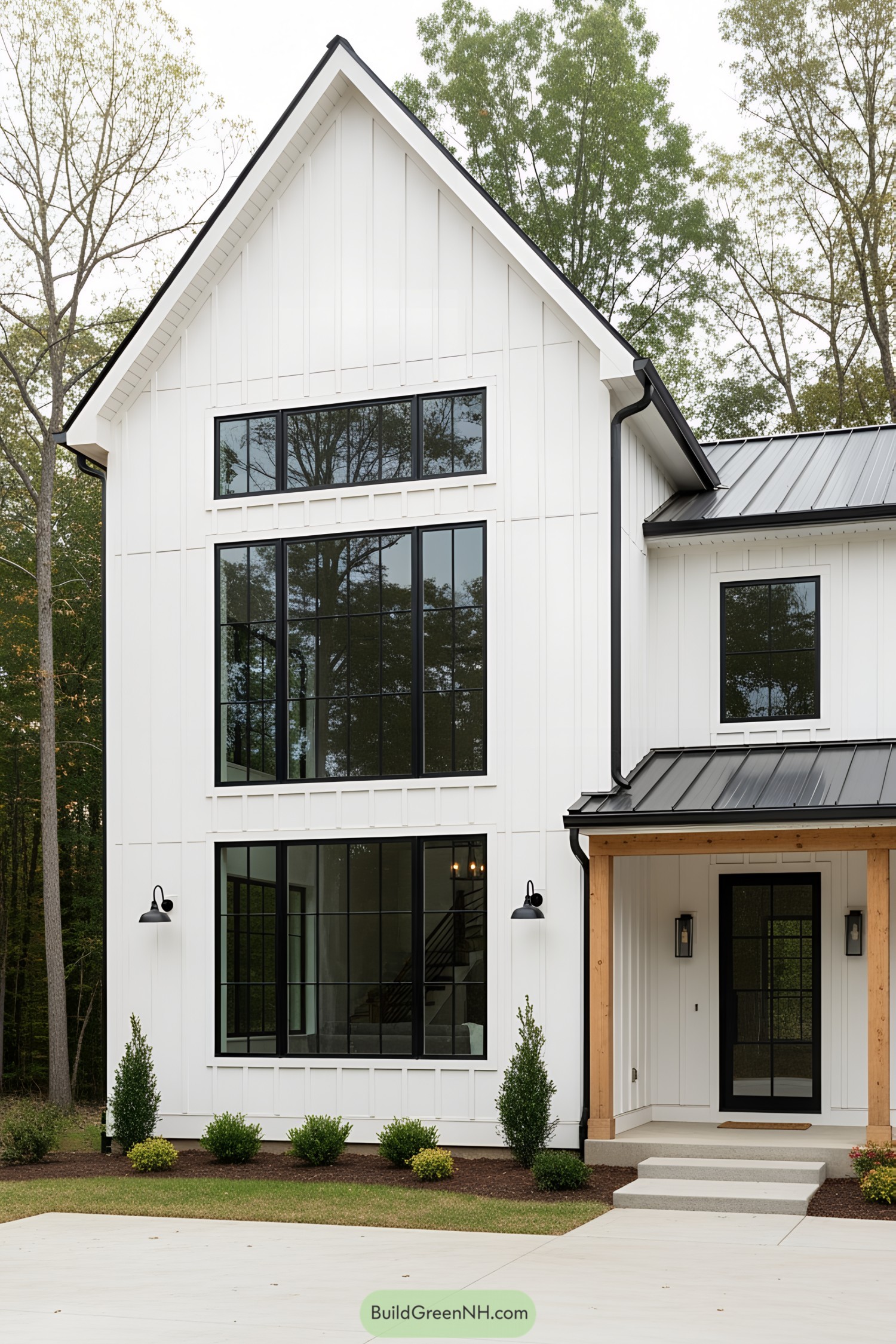 White barn house with black-framed windows and lush greenery