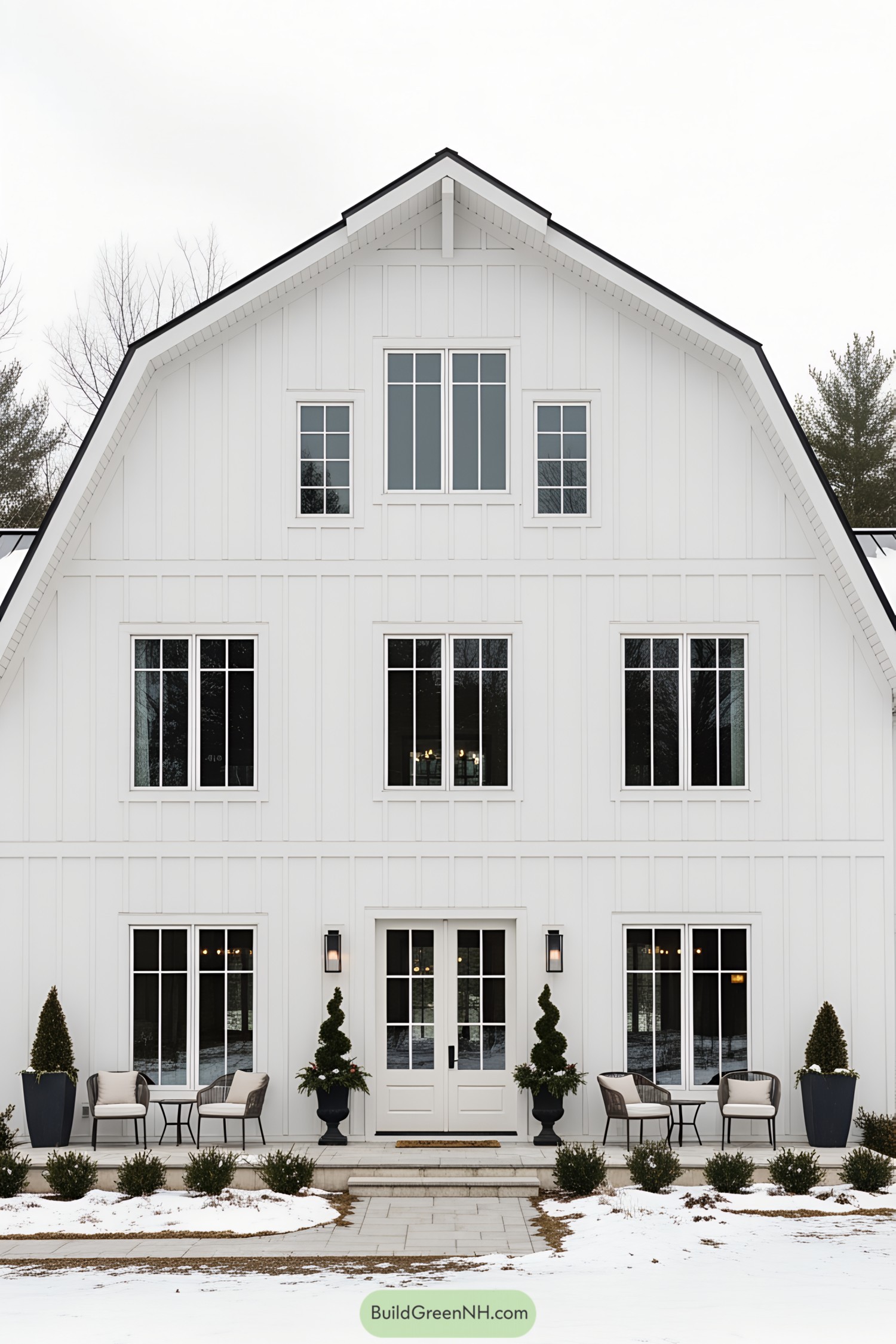 White barn house with large windows and snow-covered ground