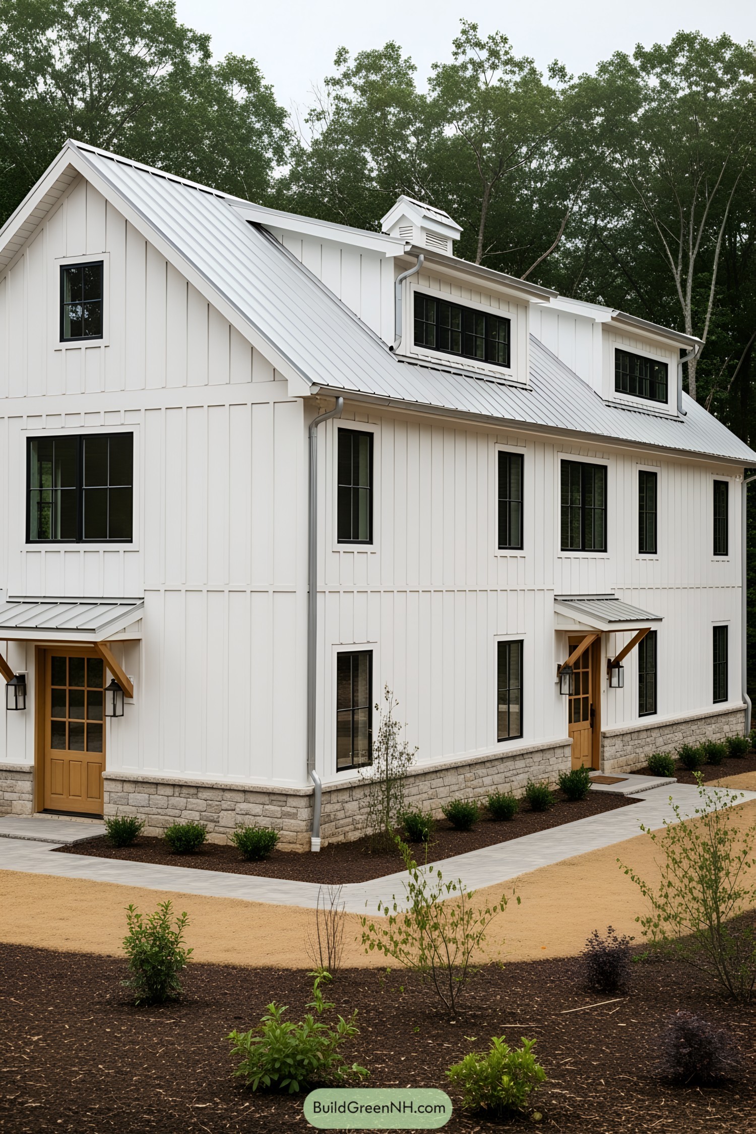 Modern white barn with black-framed windows and stone base