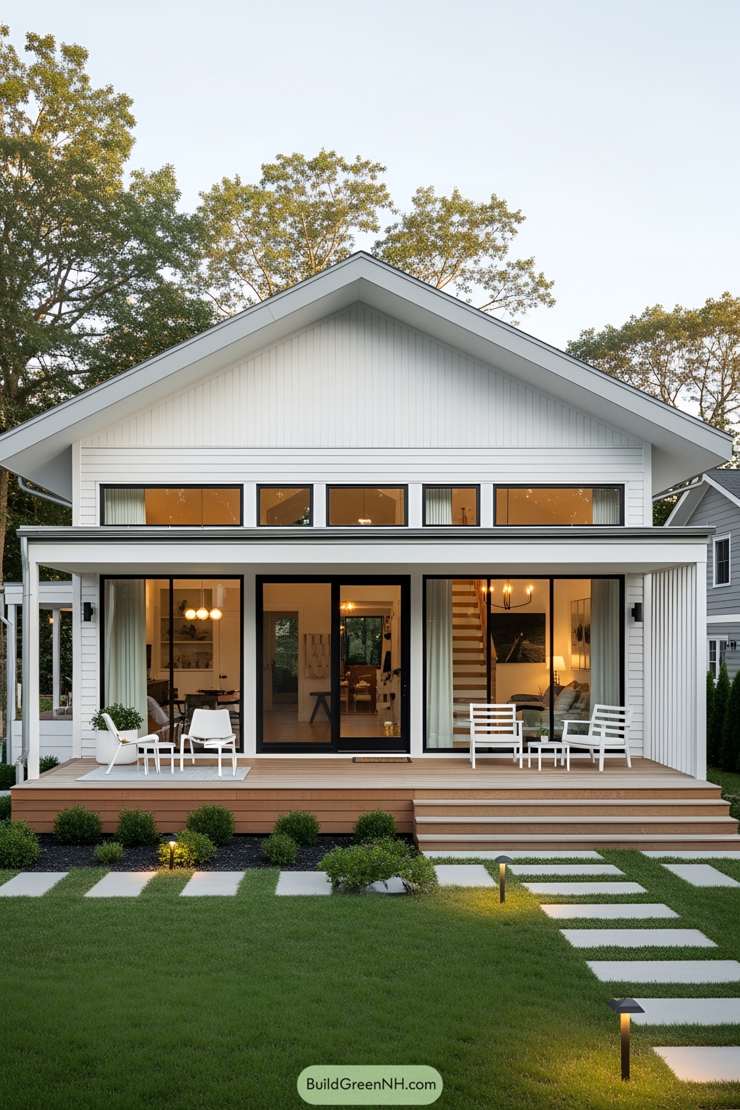 Stylish white bungalow with large windows and a wooden deck