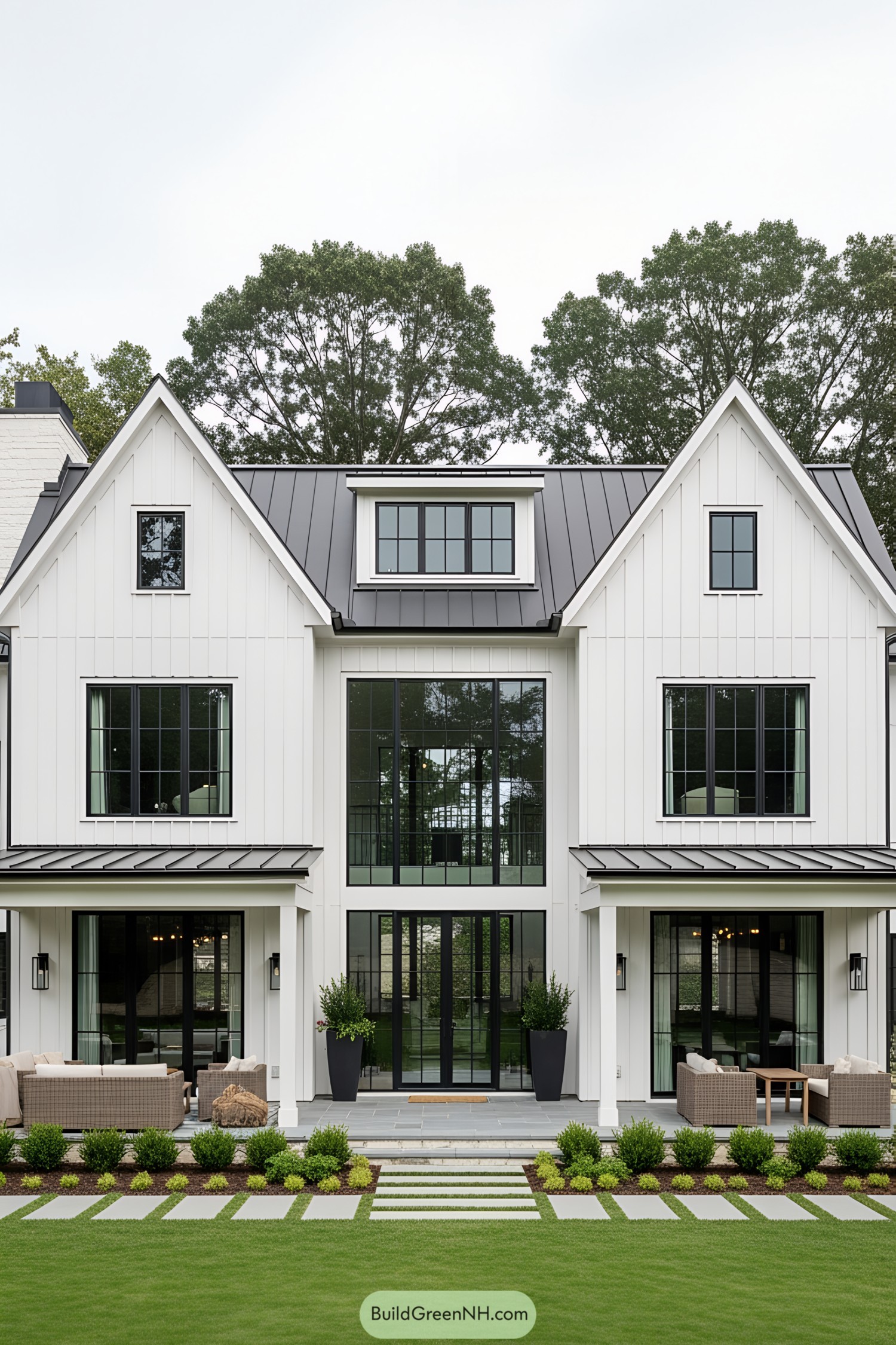 Modern white barn house with black windows and lush green lawn