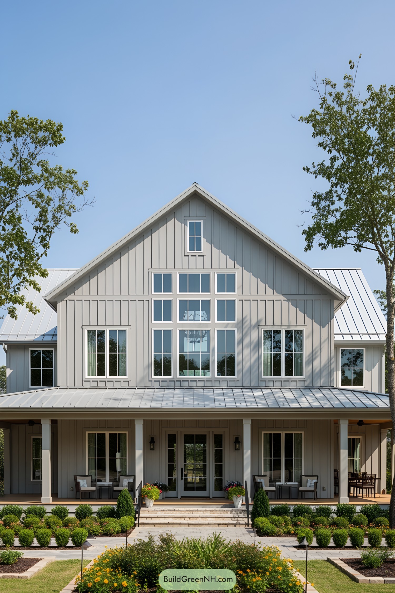 A gray barndominium with a wraparound porch and large windows