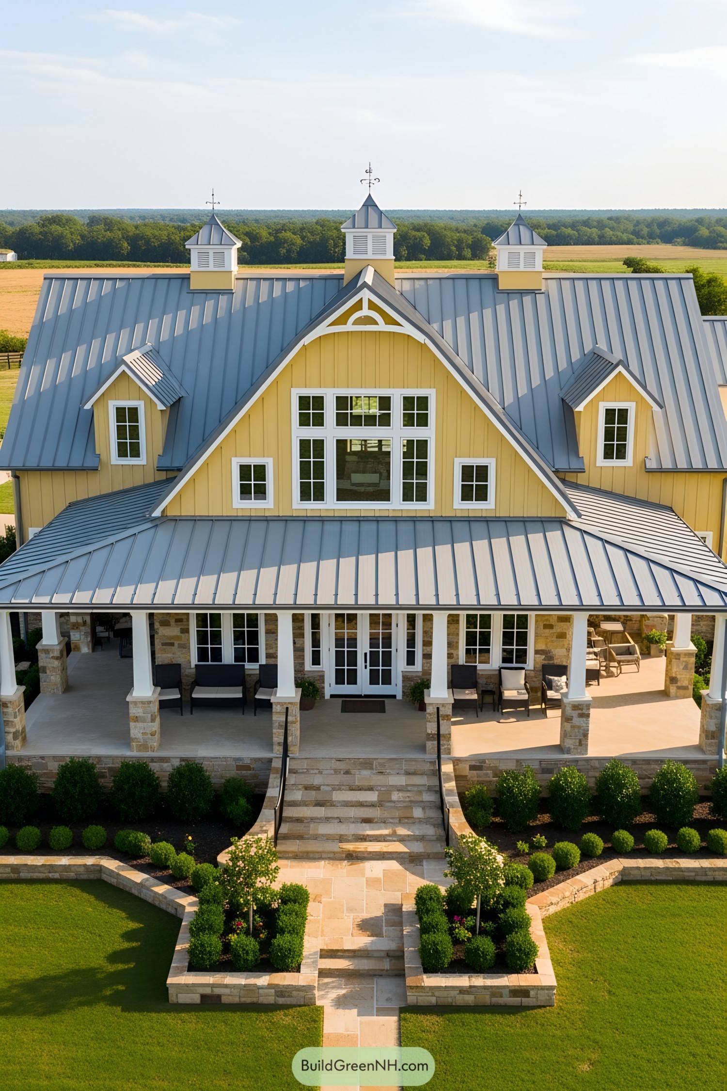 Yellow barndominium with large porch and green fields