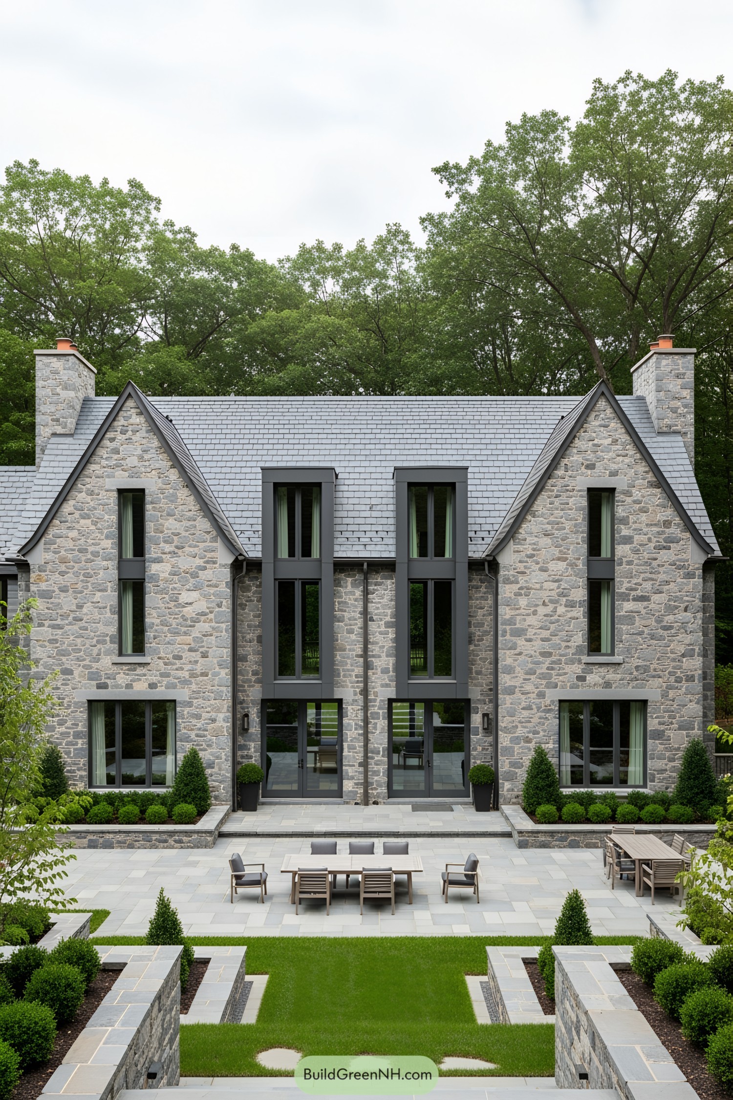 Front of a stone house with large windows and a symmetrical design