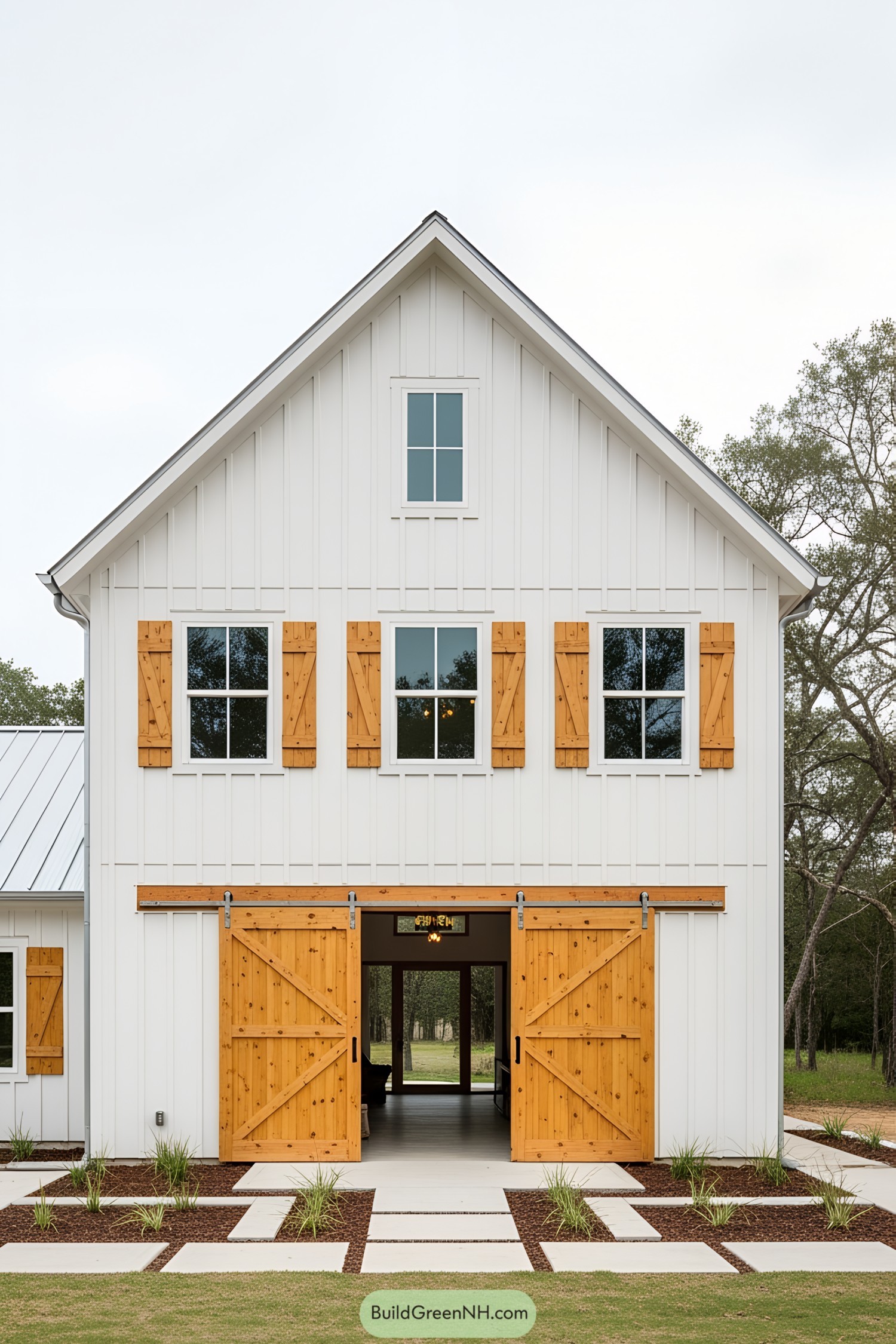 White barn house with large wooden doors and a gabled roof
