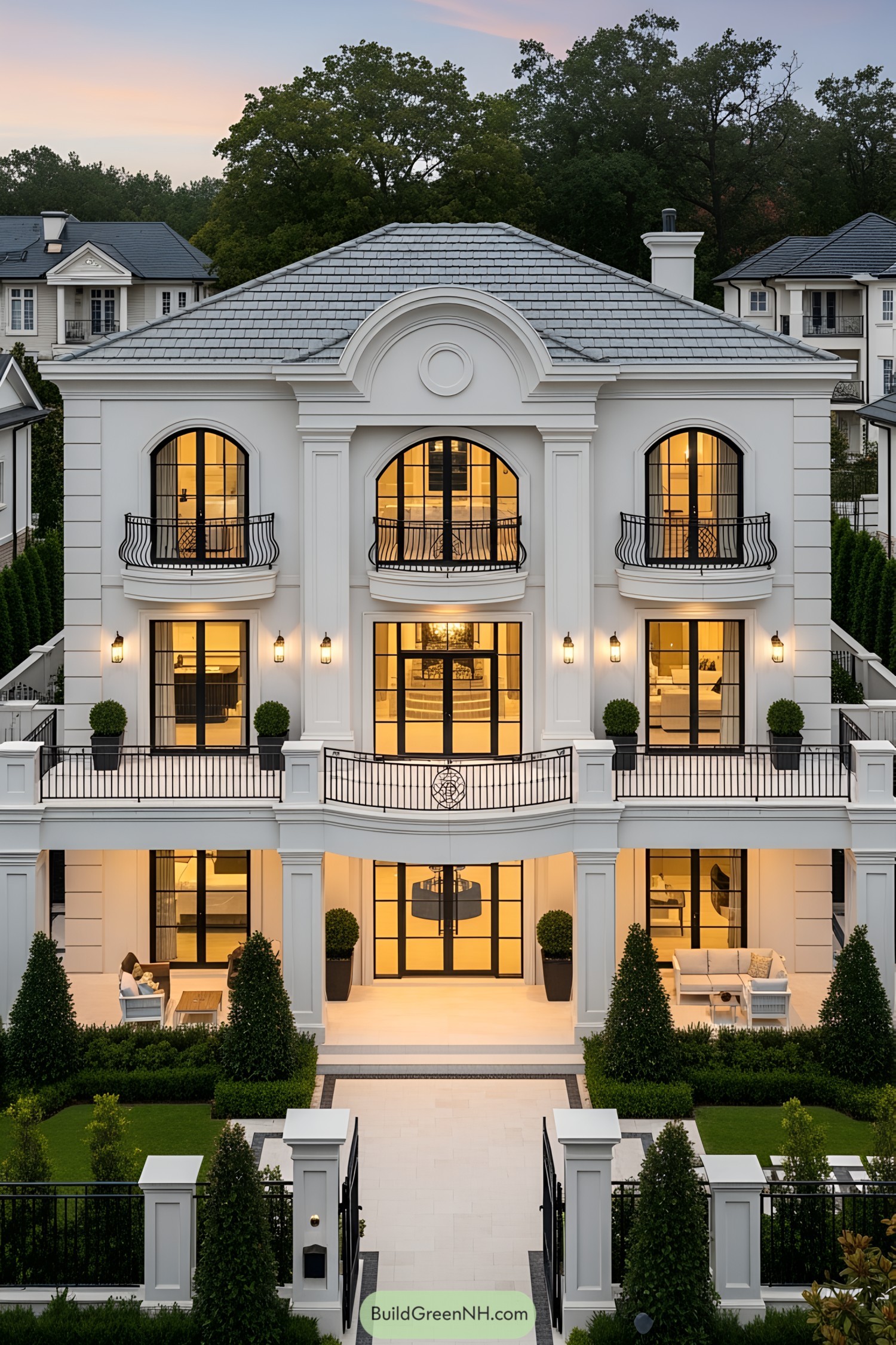 Luxurious three-story white villa with glowing windows and manicured gardens