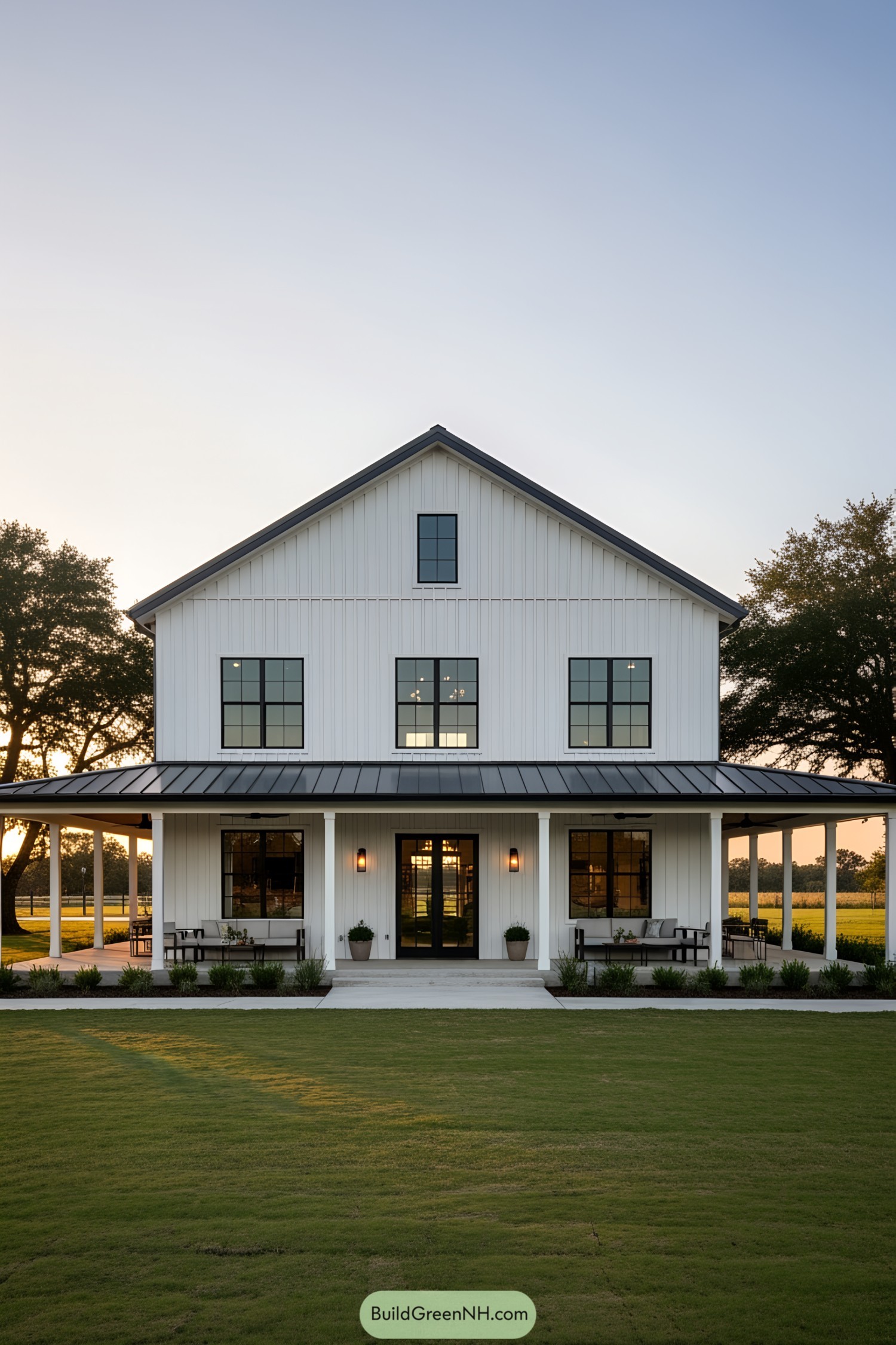 White barnhouse with a wraparound porch and sunset view