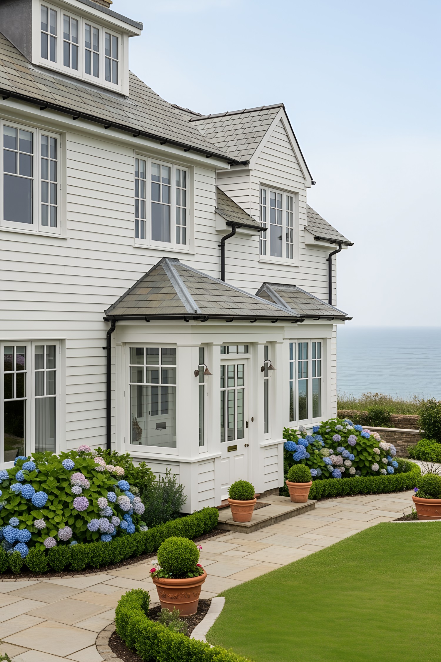 White coastal house with hydrangeas, overlooking the sea