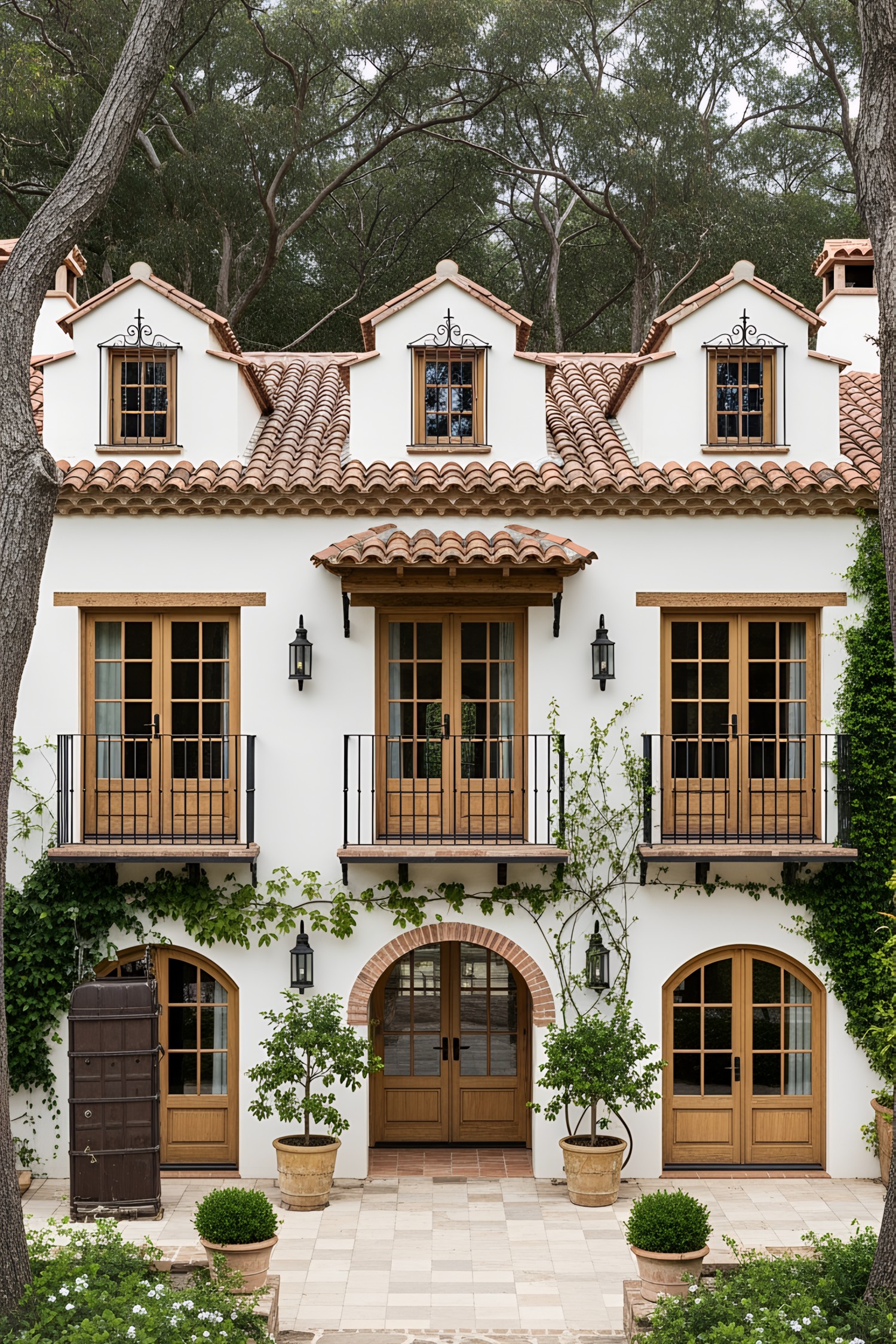 Facade of a classic Spanish farmhouse with large wooden doors and lush greenery