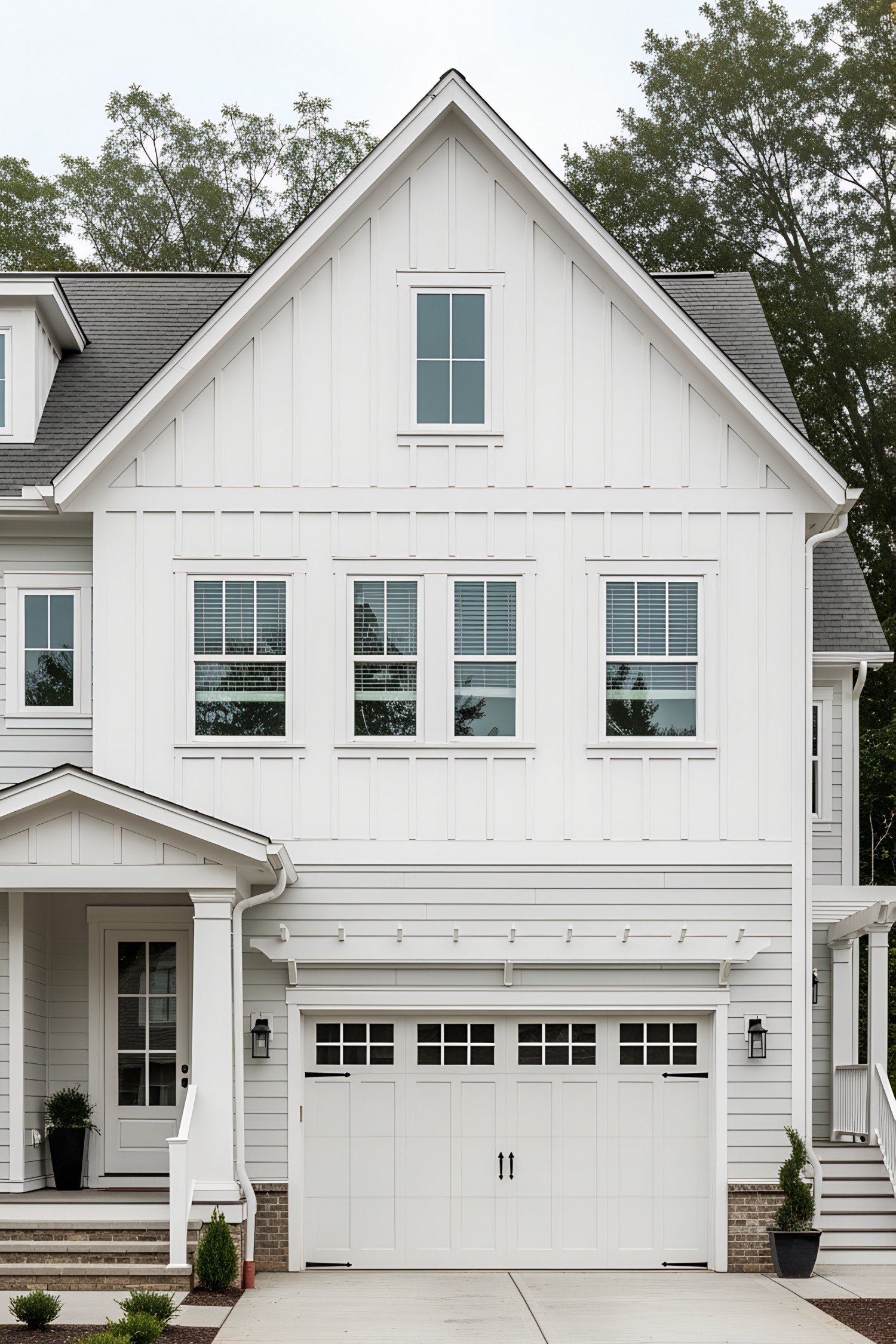 White farmhouse with attached garage and trees in the background