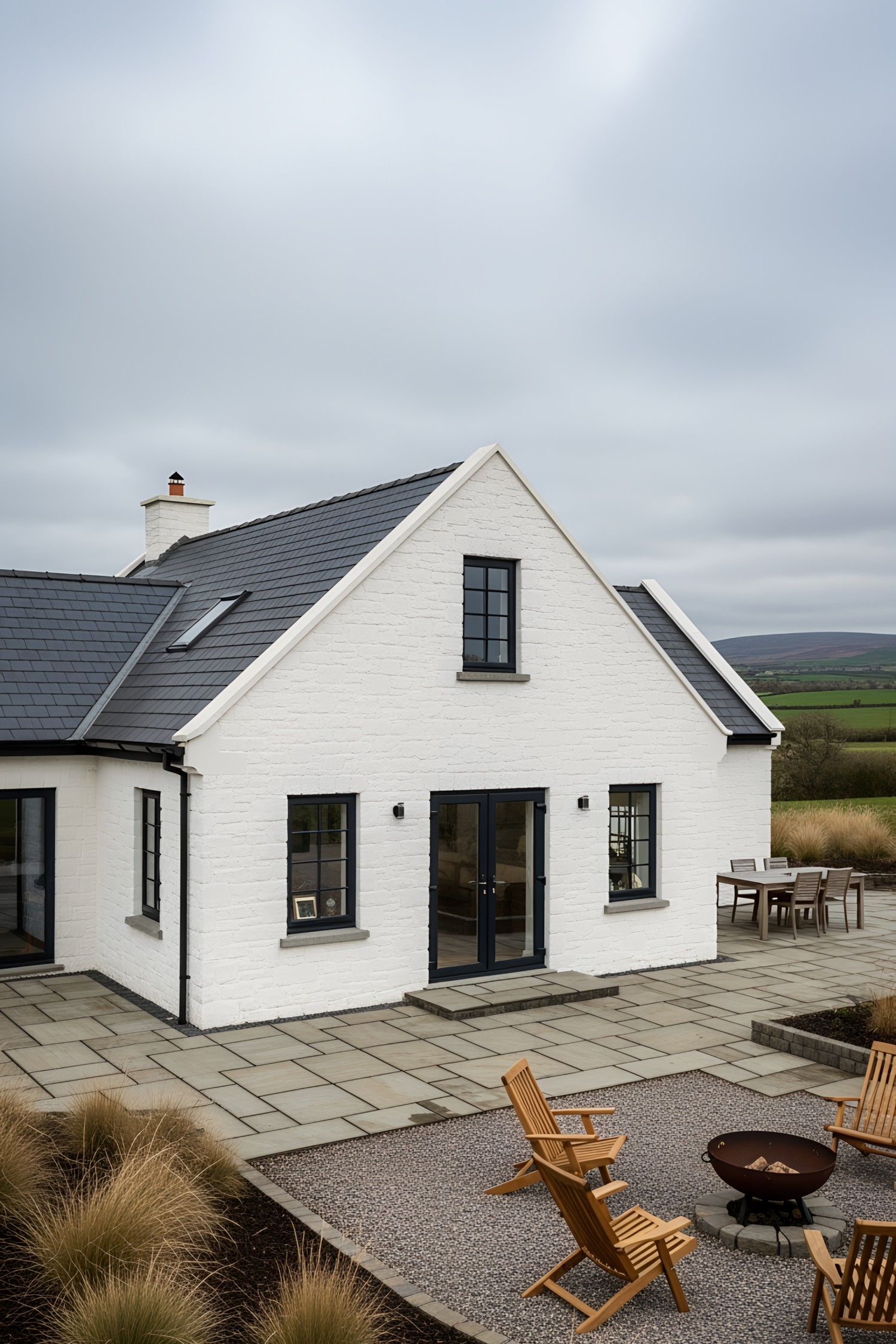 Charming white bungalow with slate roof and cozy outdoor seating