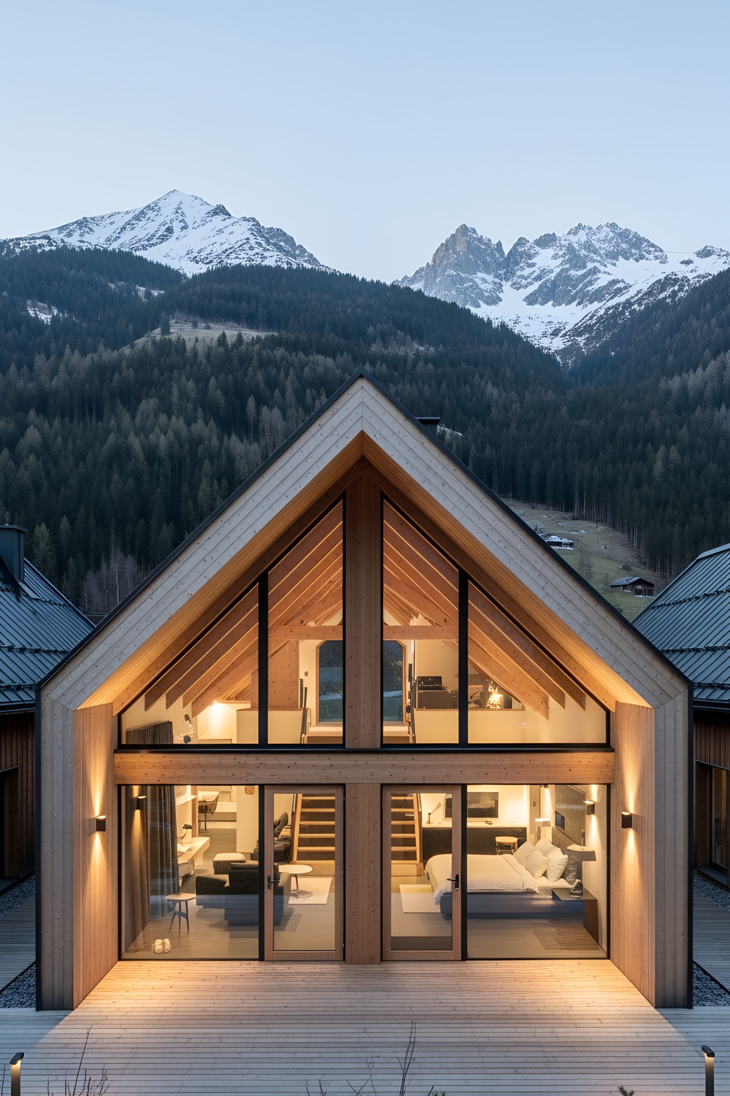 Modern wooden lodge with floor-to-ceiling windows set against a snowy mountain backdrop
