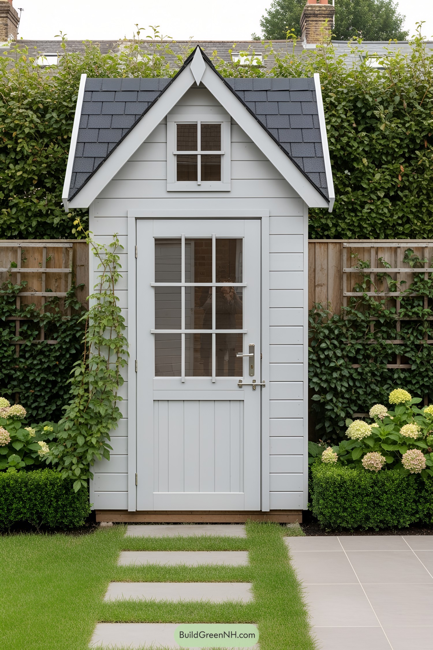 Compact white shed with gabled roof, framed by greenery