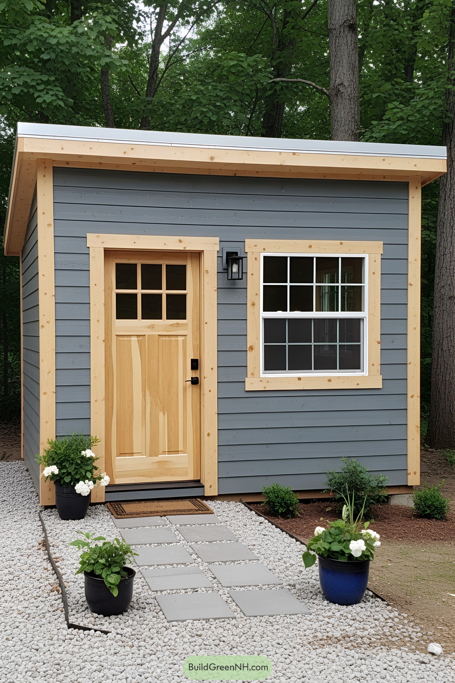 A small gray shed with a wooden door and plants outside