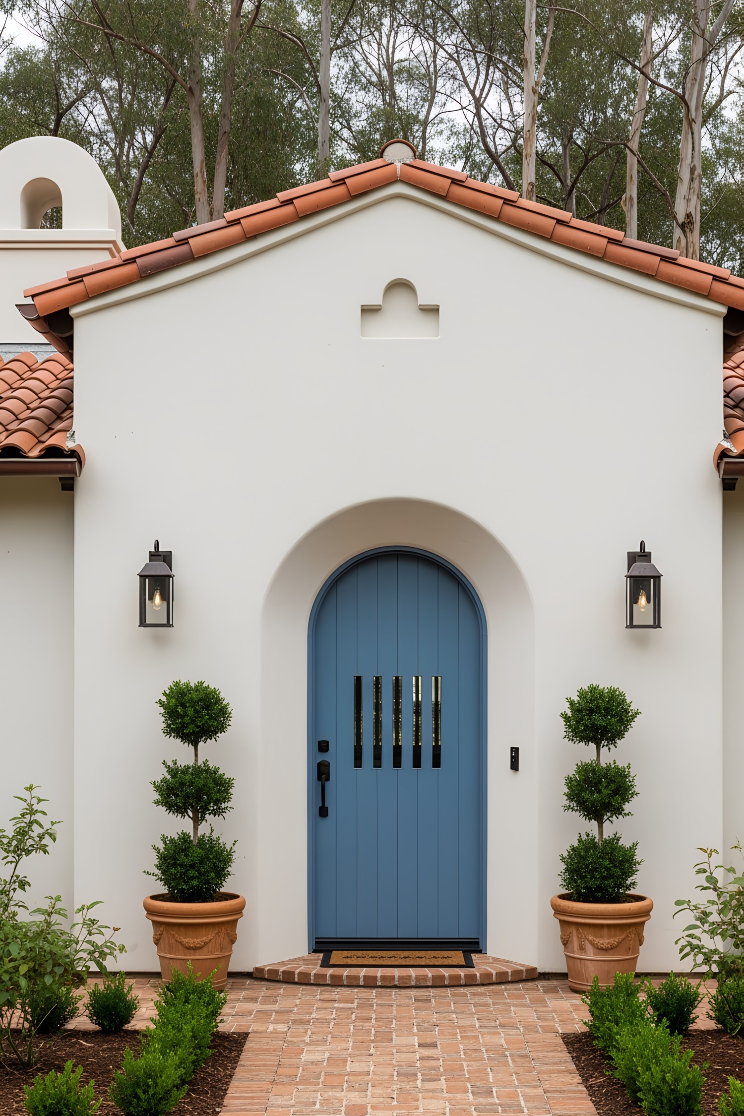White coastal house with a blue door and terracotta roof