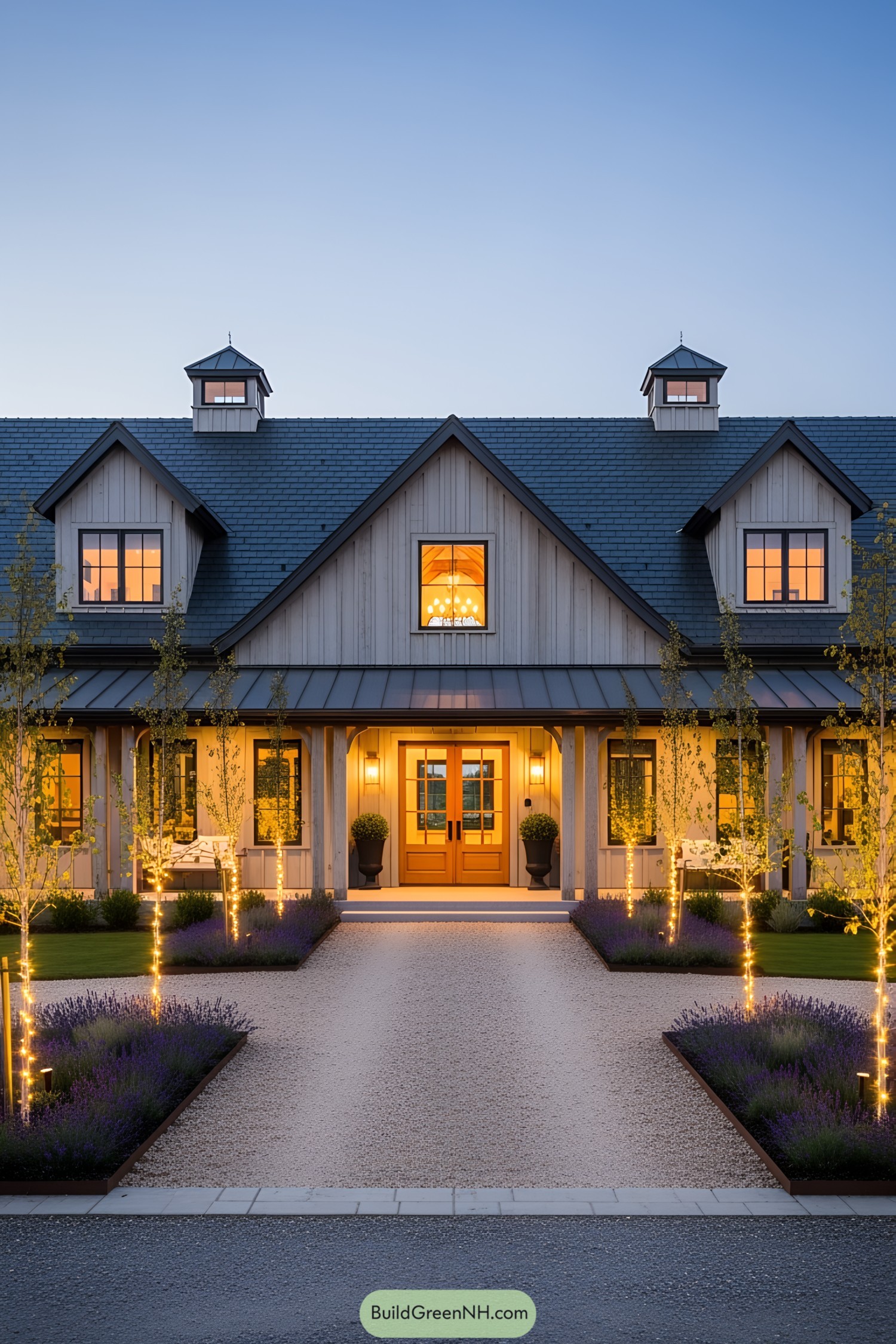 Modern barndominium with LED-lit trees at sunset, highlighting a serene driveway