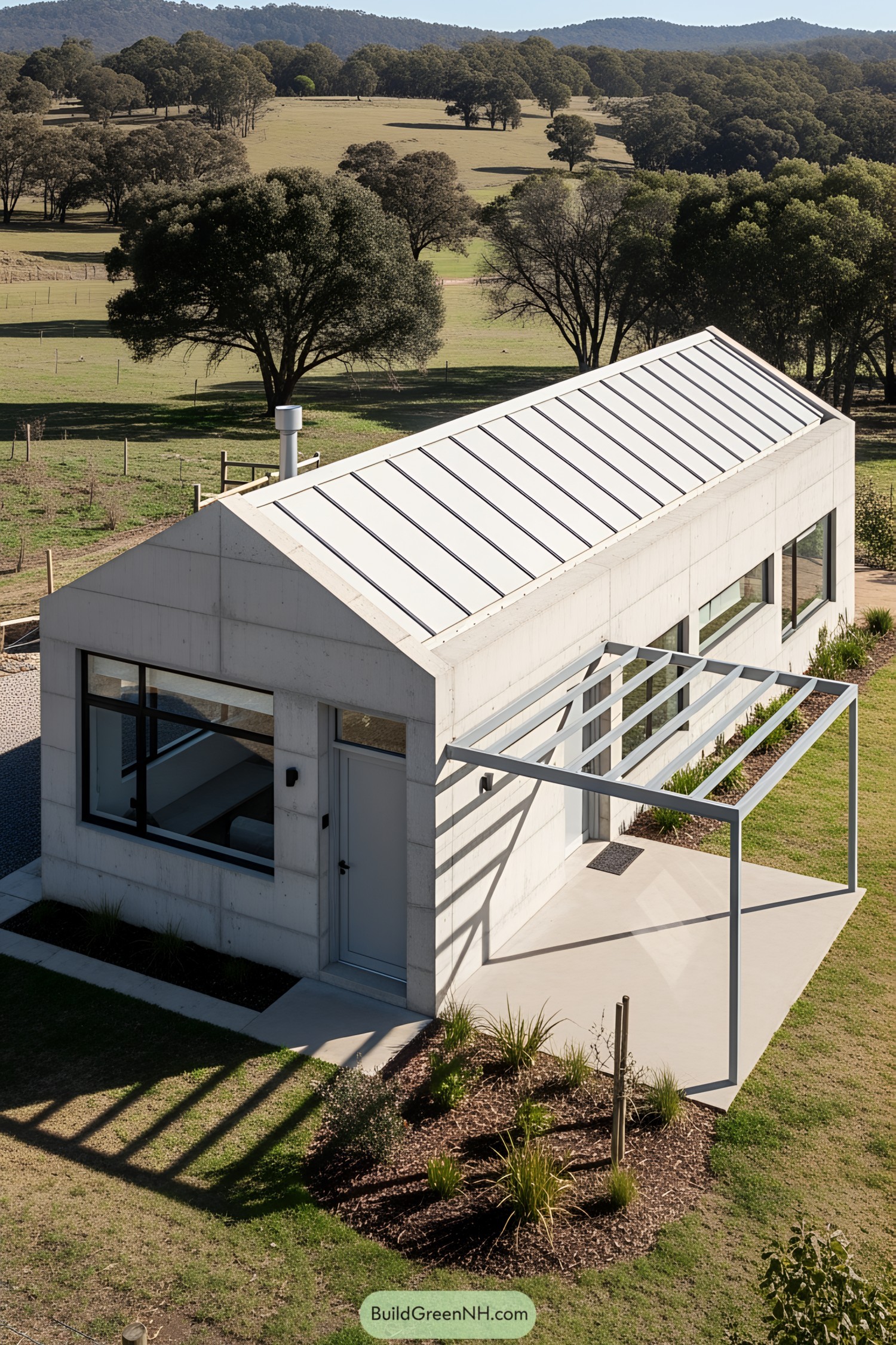 Small modern concrete house with a pitched roof in a sunny rural landscape
