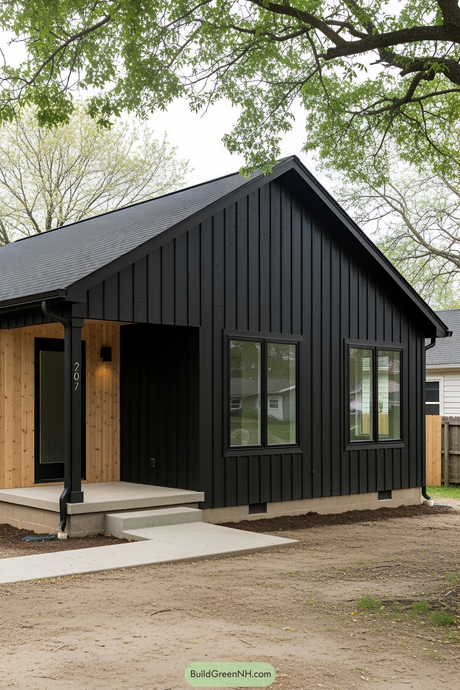 Black ranch house with wooden accents under trees