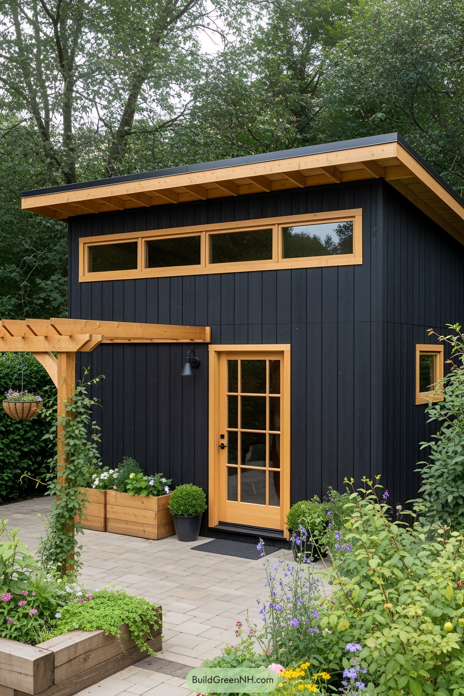 A black shed with a wooden door surrounded by greenery