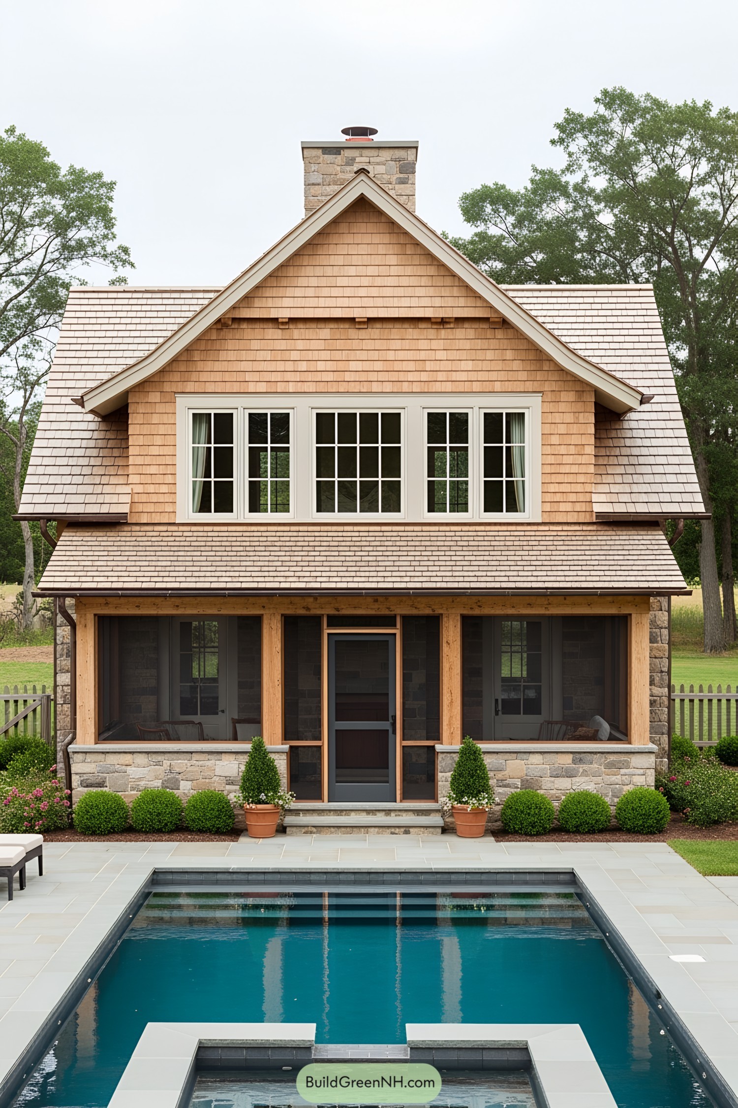 Pool house with wooden shingles and large windows overlooking a pool