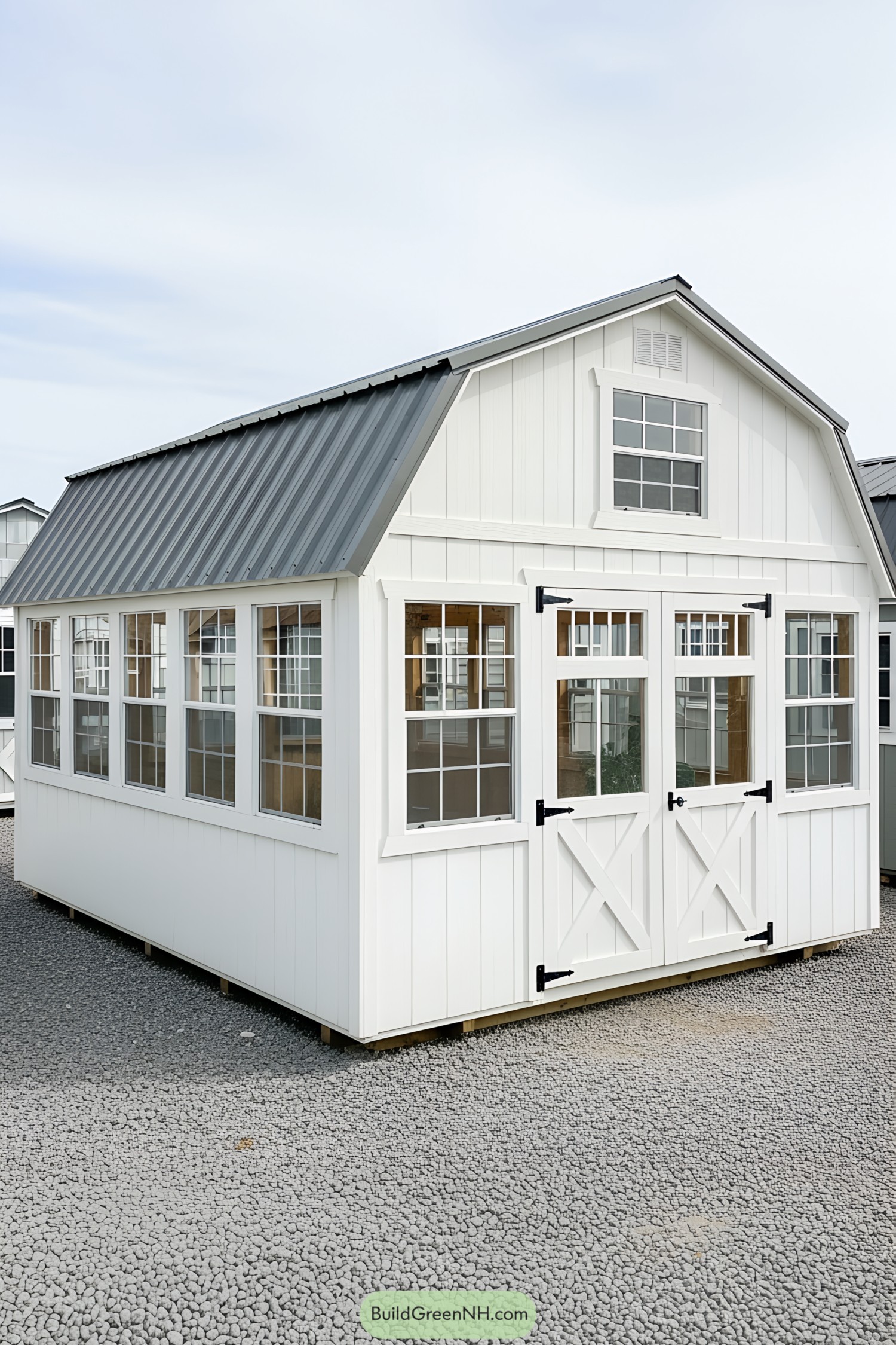White greenhouse shed with a black roof and multiple windows
