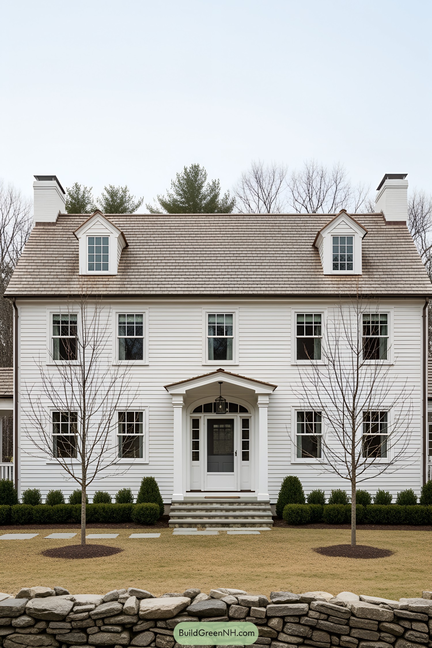 White farmhouse with stone wall in foreground