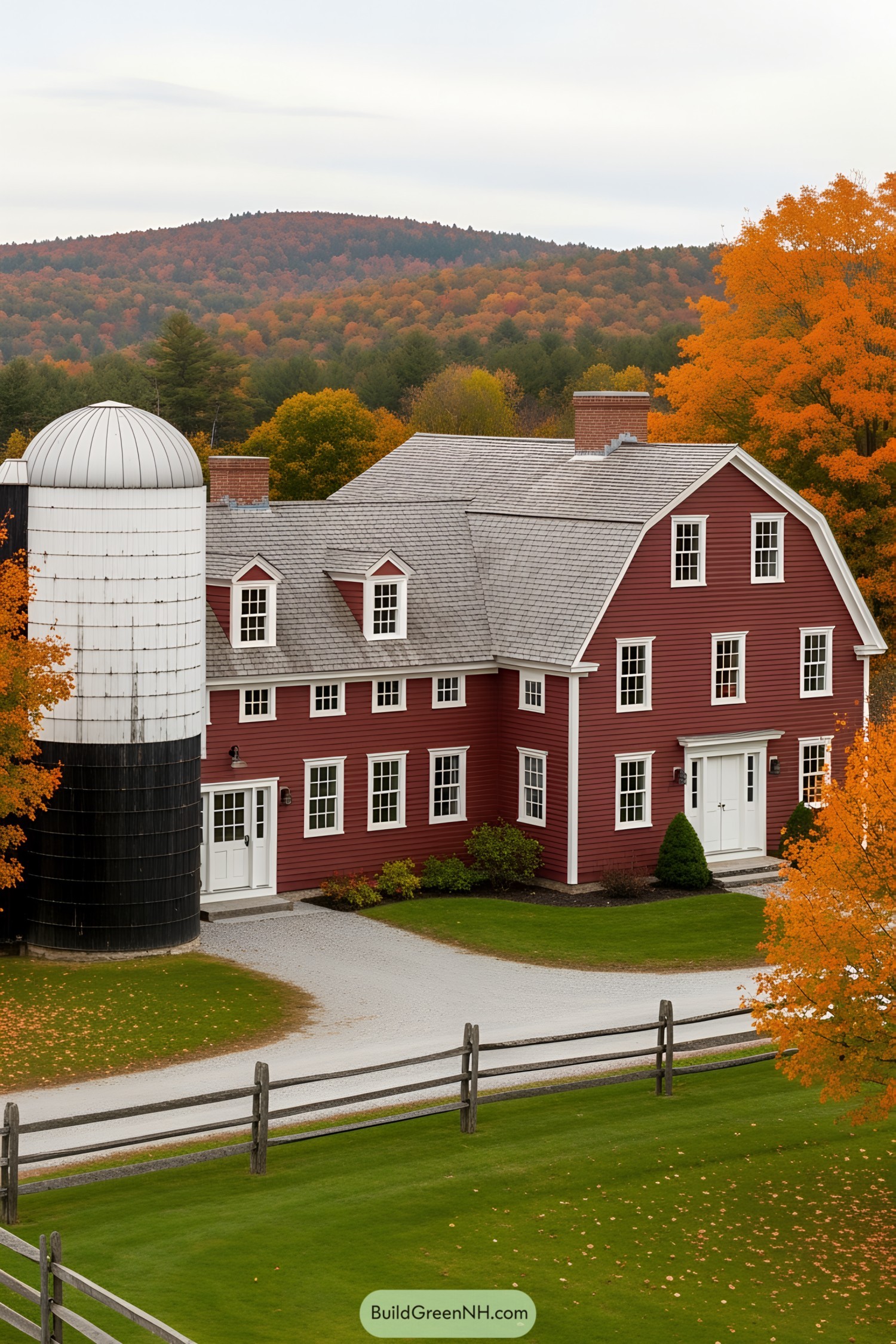 Red farmhouse with attached silo surrounded by autumn trees