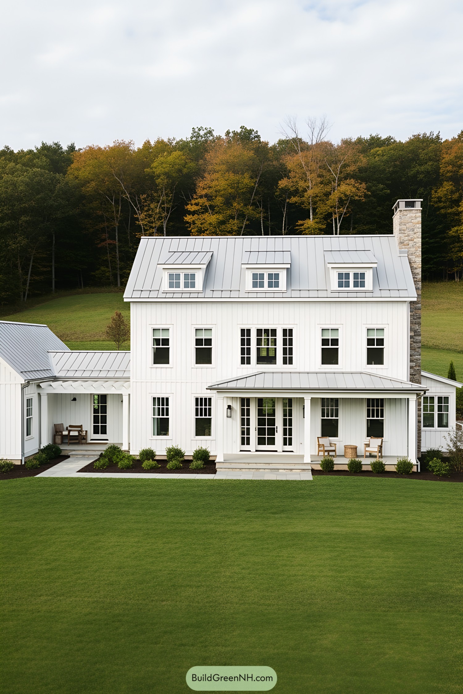 White farmhouse with metal roof against autumn foliage