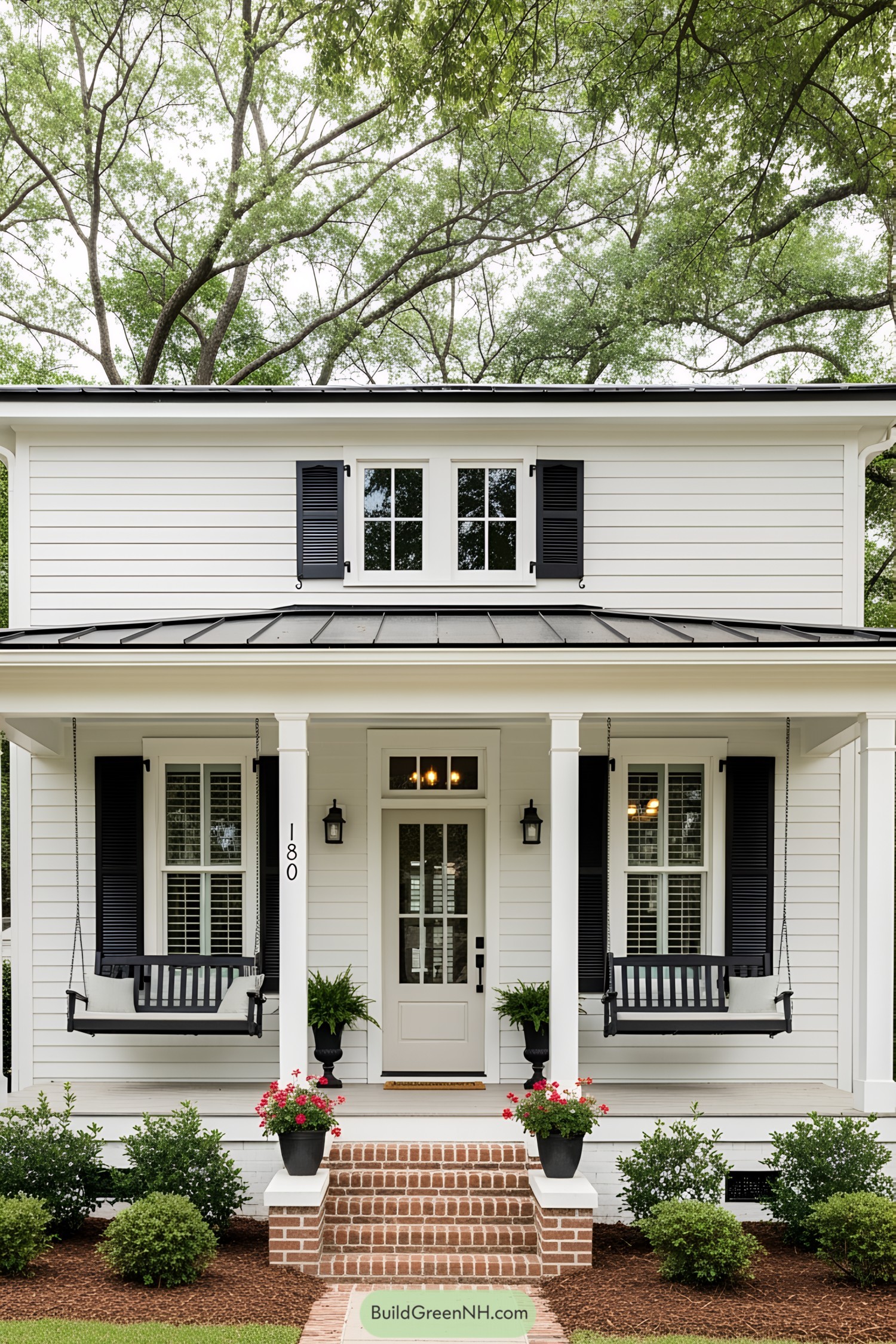 White house with black shutters and porch swings under leafy trees