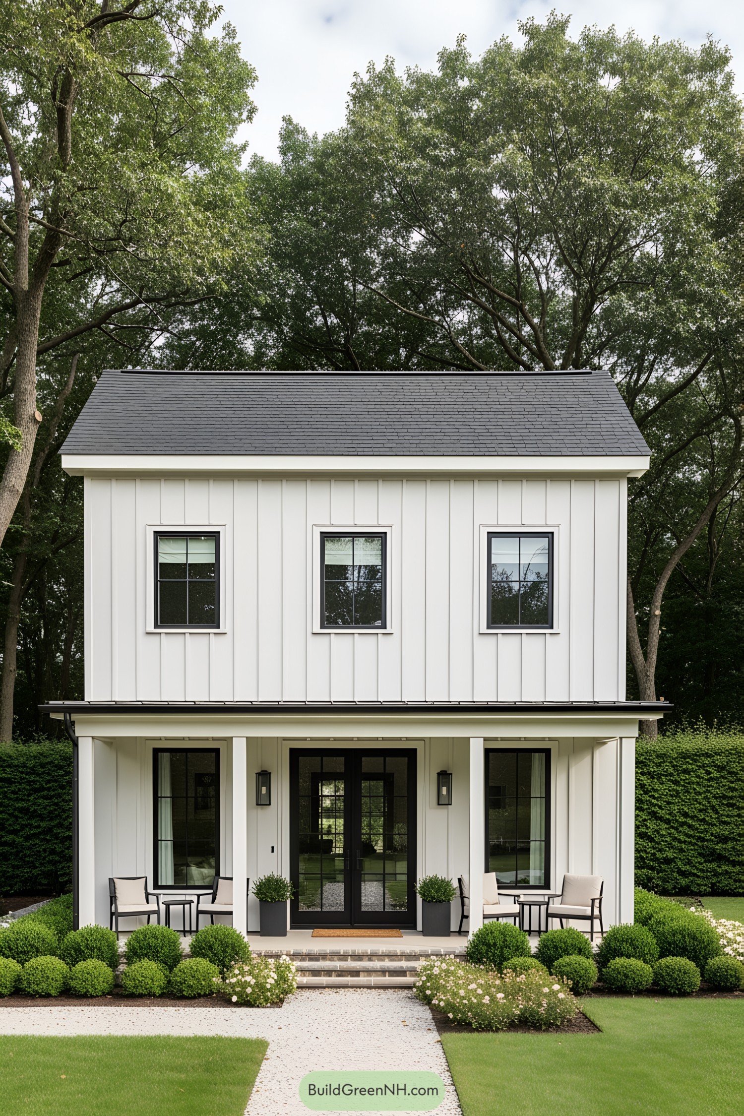 White farmhouse with black trim and lush greenery