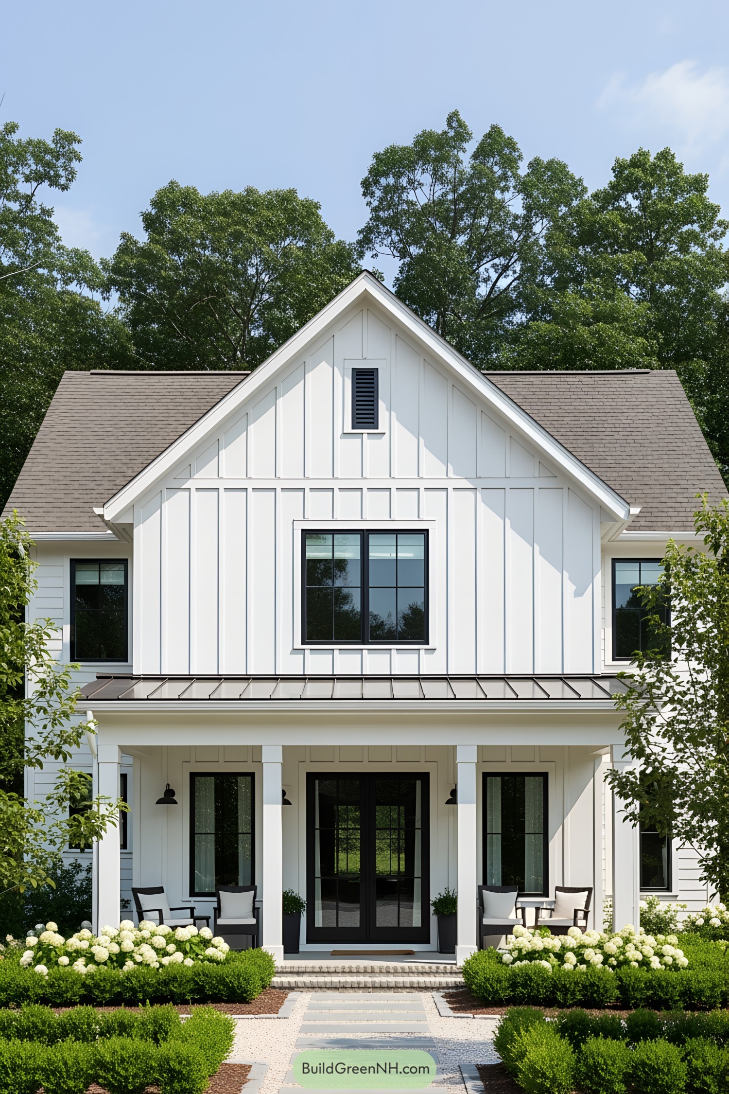 White farmhouse with a gable roof, surrounded by lush greenery
