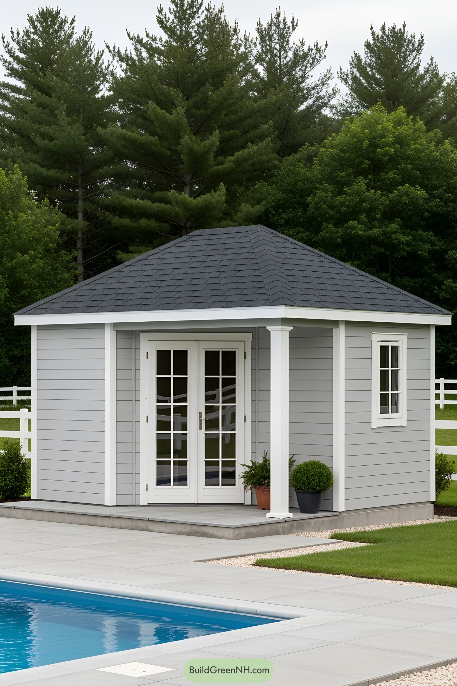 Small grey pool house beside a pool and trees