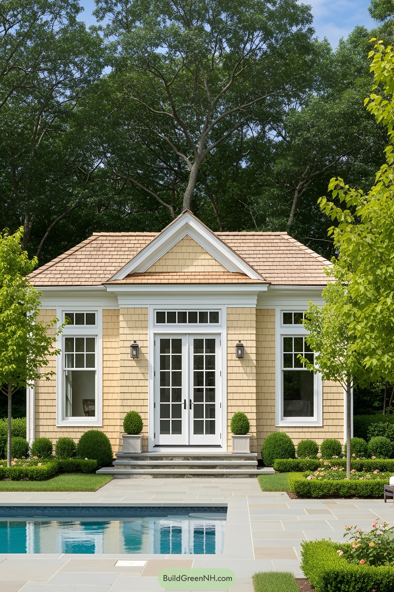 Pool house with shingle siding and formal landscaping