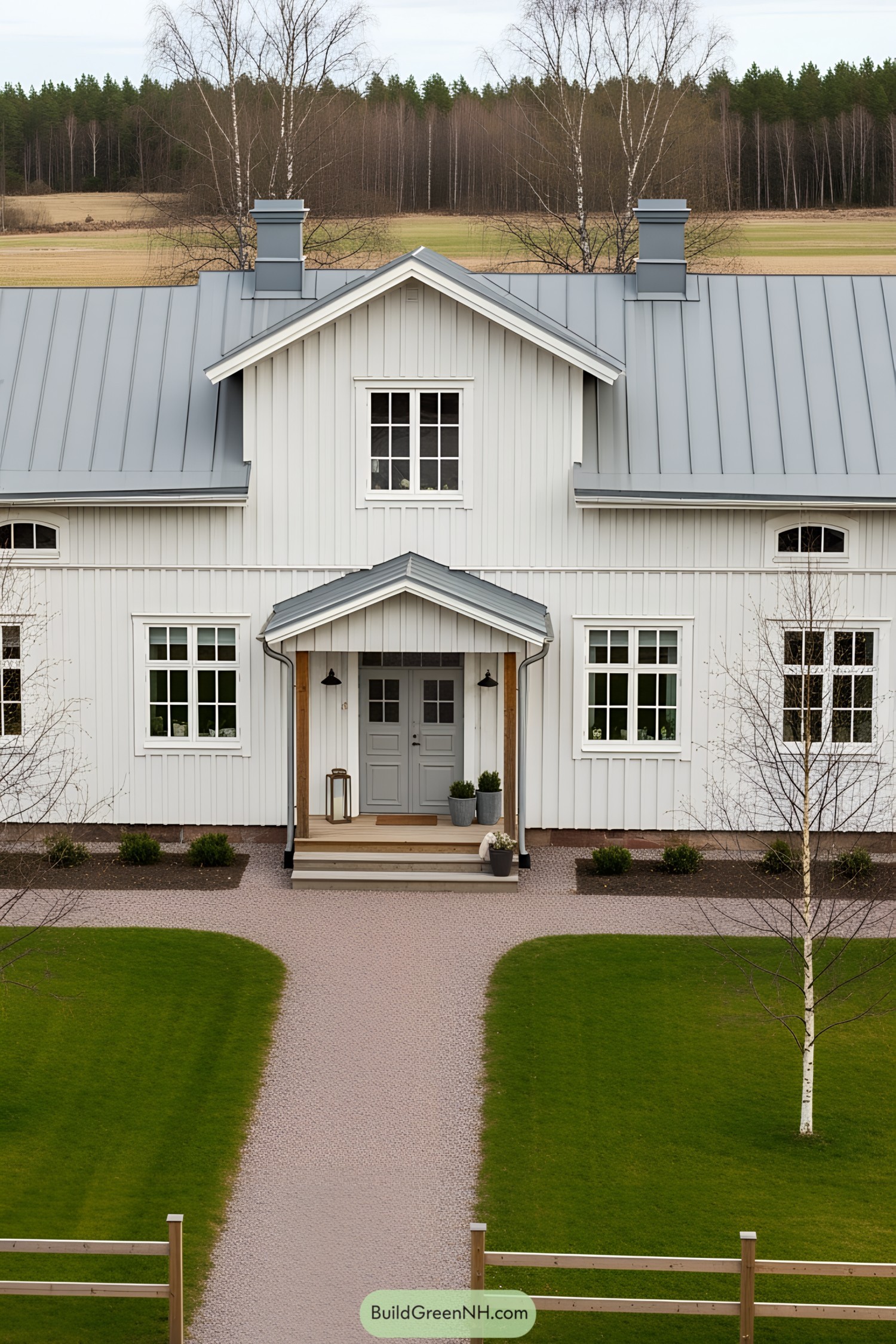 White farmhouse with a grey roof and porch in a countryside setting