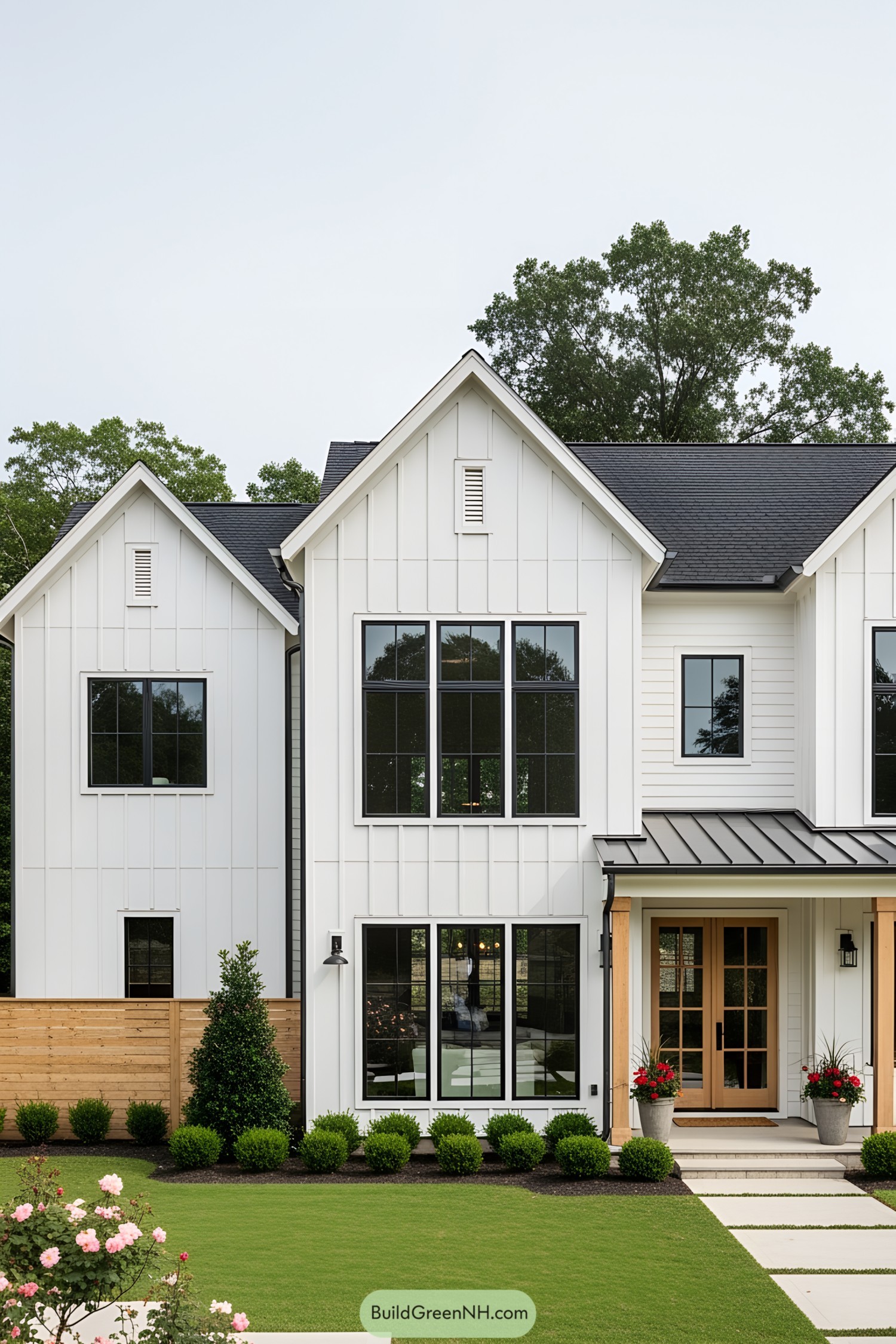 Modern white farmhouse with large windows and a manicured lawn