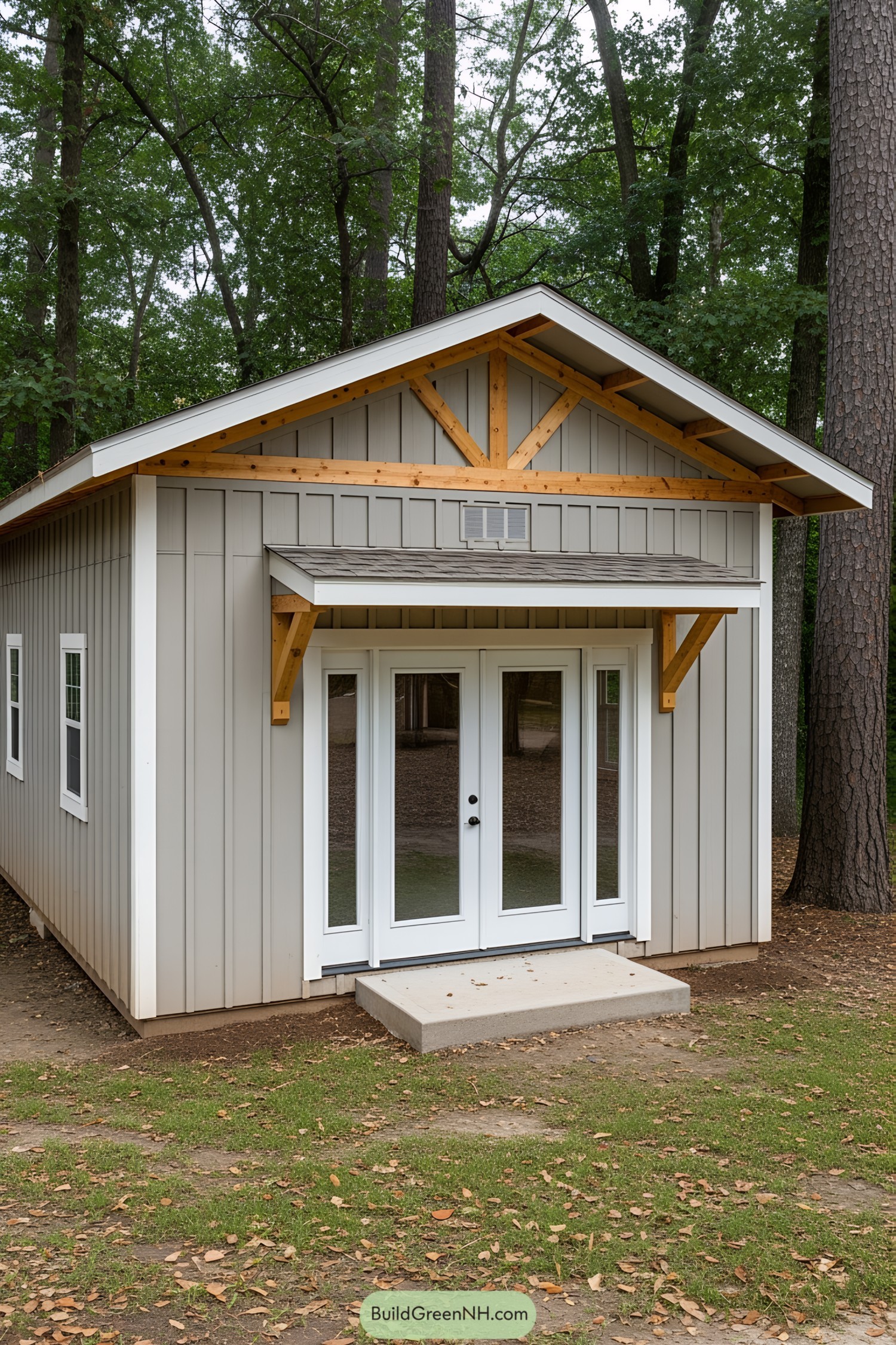 Small gray shed with French doors in a wooded area