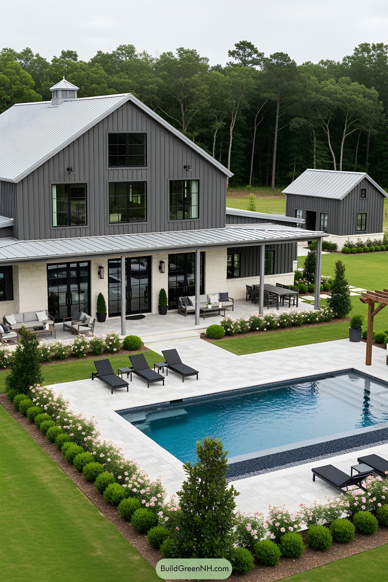 Barndominium with poolside lounge chairs and lush landscaping