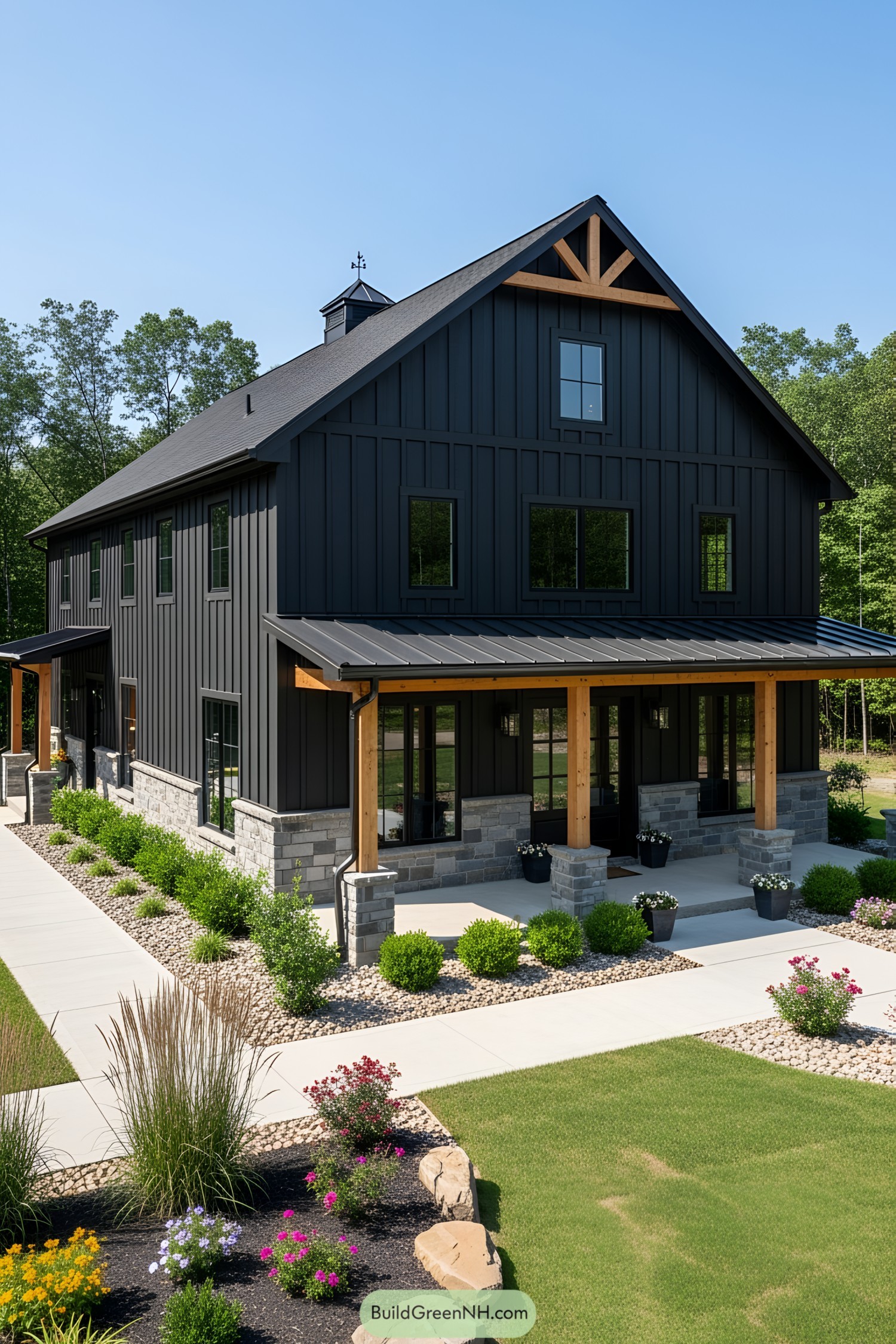 Black barndominium with stone accents and a manicured garden