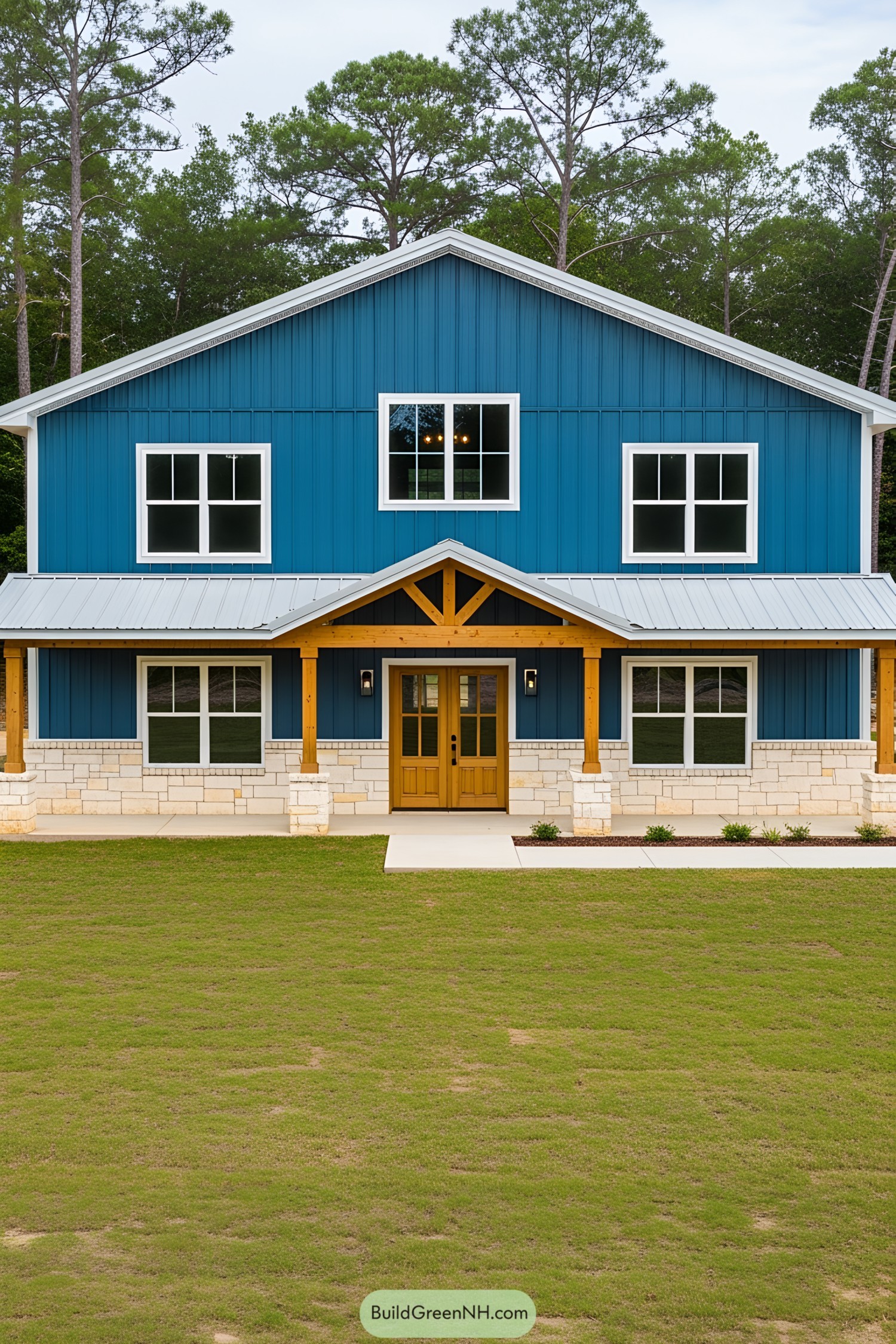 Blue barndominium with a wooden porch and windows