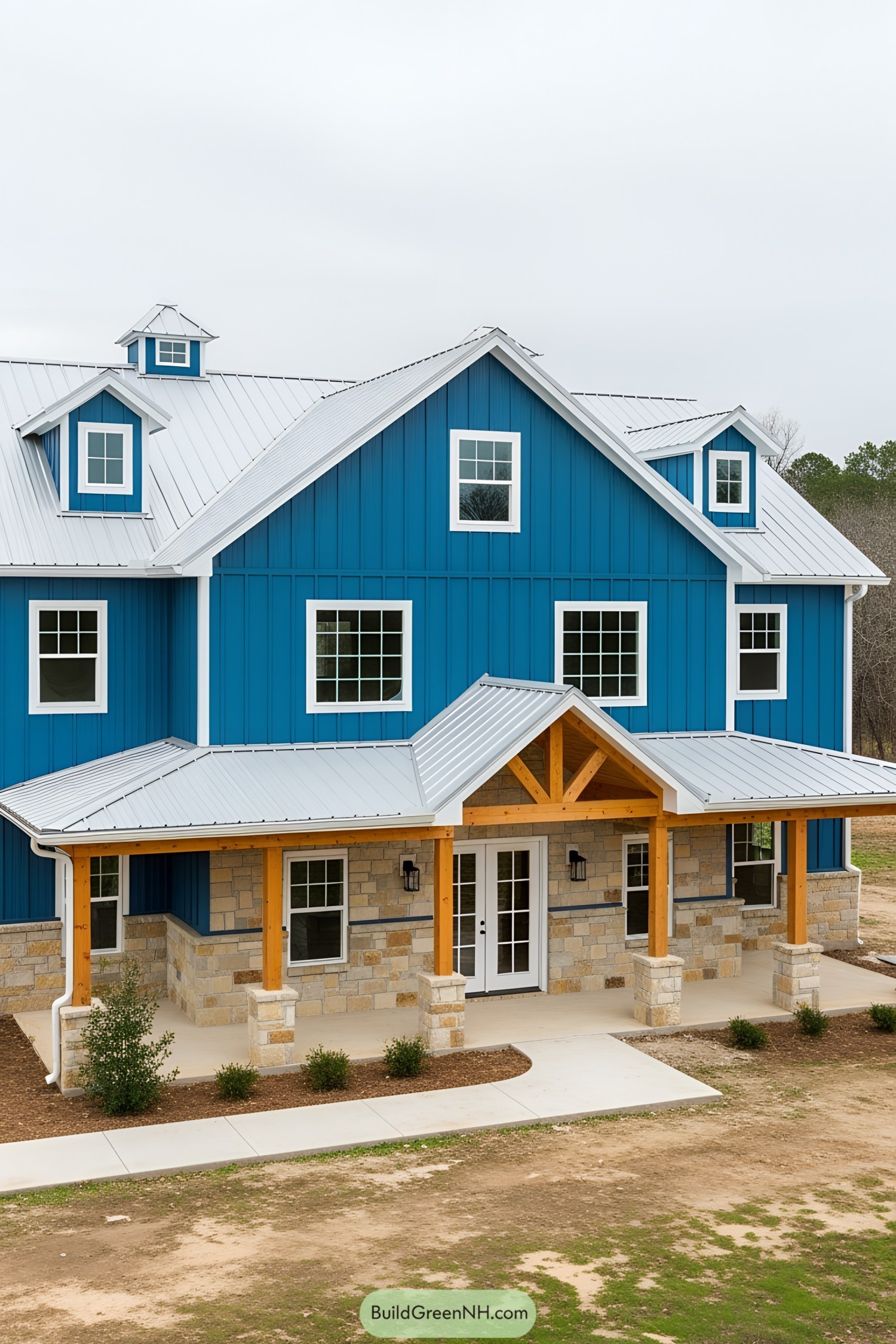 Blue barndominium with stone accents and white roof