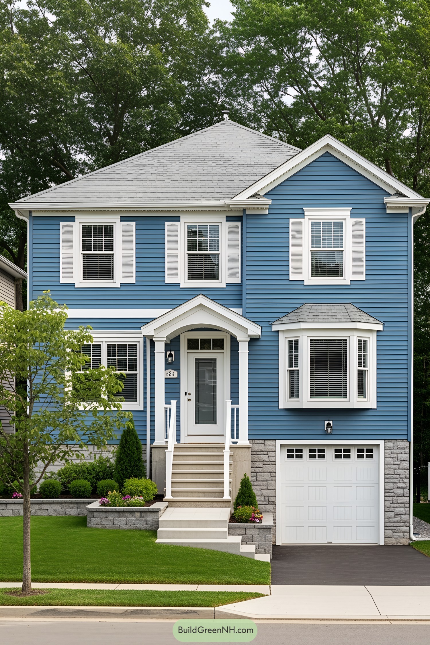 Contemporary blue suburban home with white accents and lush greenery