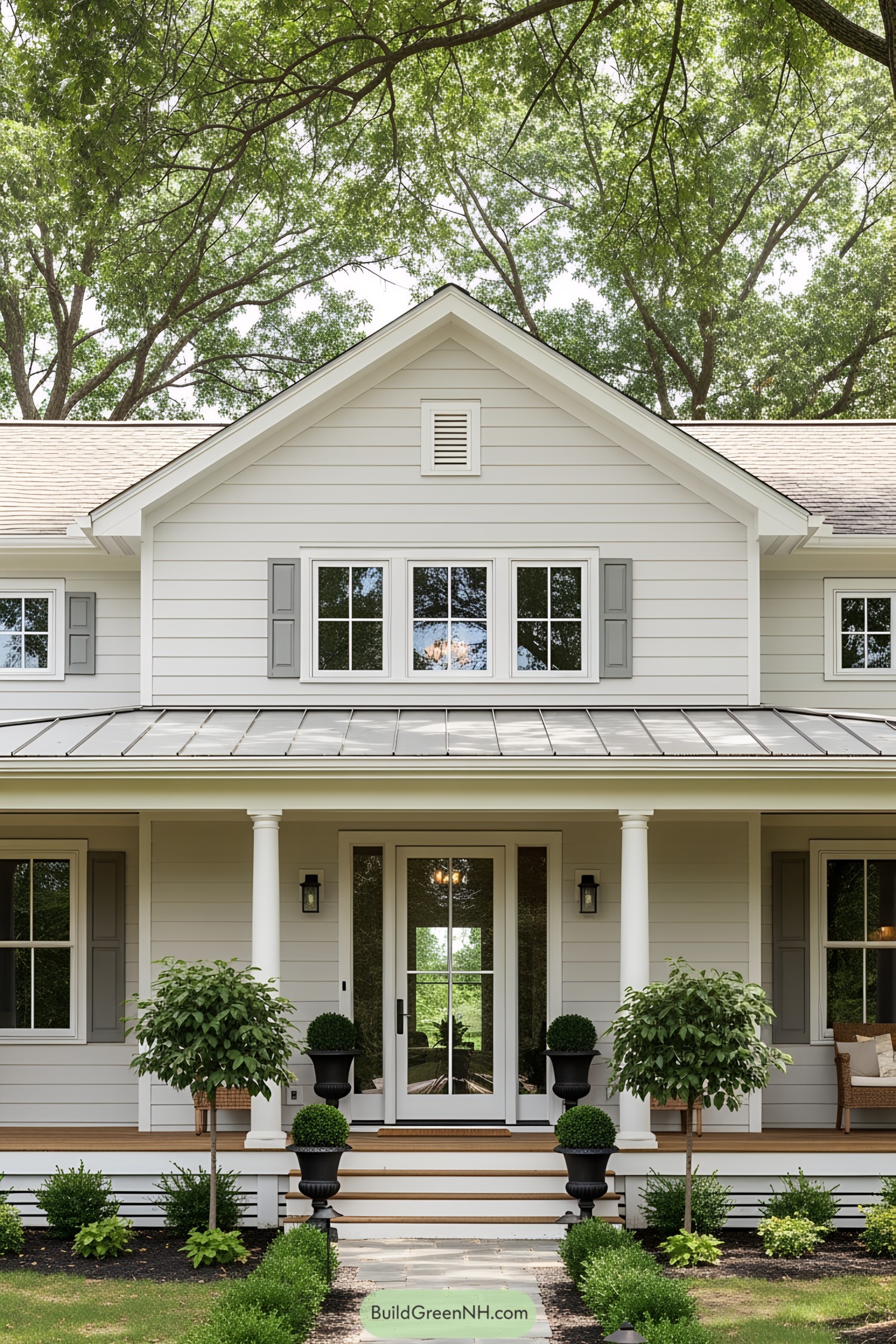 Front view of a charming farmhouse with columns and lush greenery