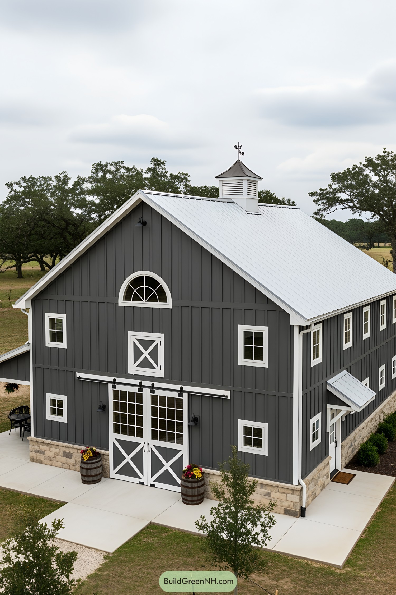 Barn house with gray siding and white accents, featuring a cupola on the roof